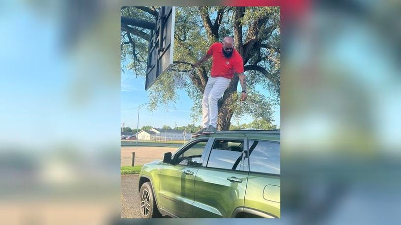 Cedric Burns-Davis, 38, stands on top of his Jeep as he installs a new basketball net at one of the city parks. He has replaced about 15 nets so far. CONTIBUTED