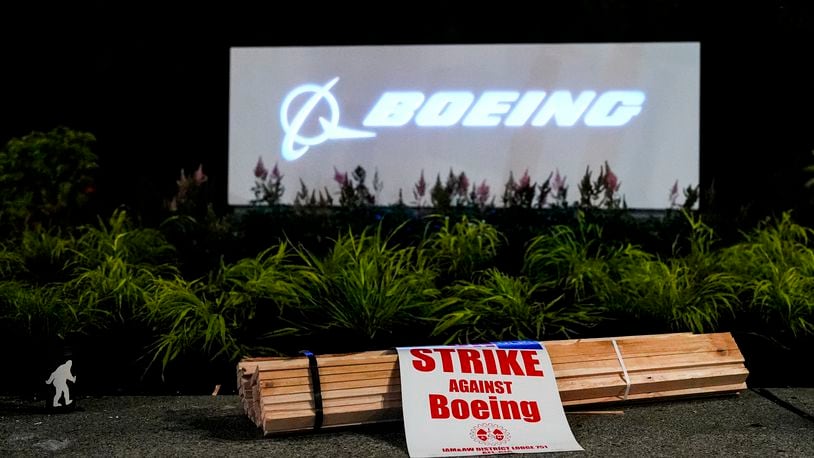 Signs and firewood sit in front of a Boeing sign as employees picket after union members voted overwhelmingly to reject a contract offer and go on strike Friday, Sept. 13, 2024, outside the company's factory in Renton, Wash. (AP Photo/Lindsey Wasson)