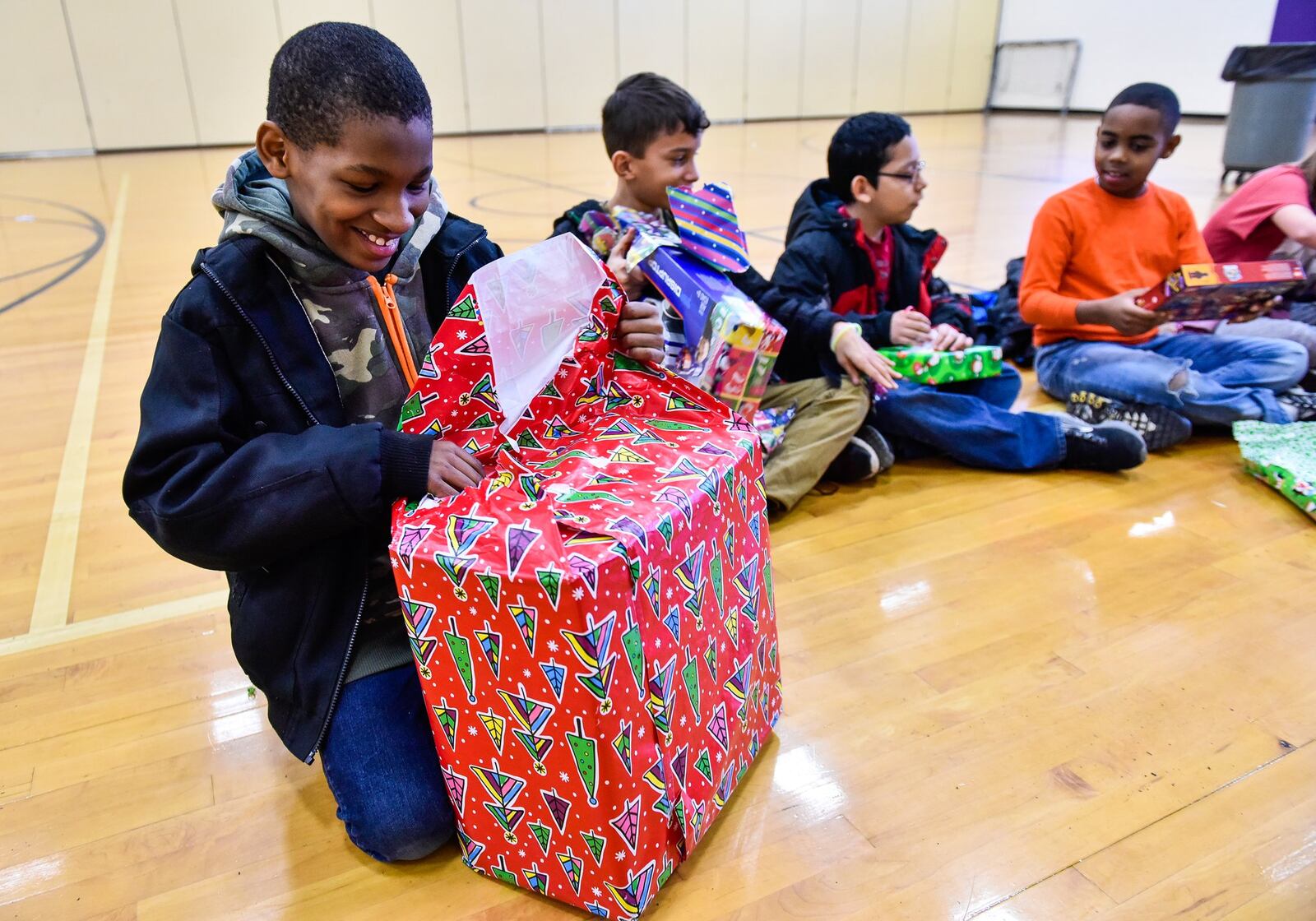 Fifth-grader Jacquel Keller, left, opens a gift during a special event Wednesday, Dec. 19 at Rosa Parks Elementary School in Middletown. Students from Fenwick High School organized a toy drive to donate gifts to students at Rosa Parks Elementary School. Hundreds of presents were donated and each student at Rosa Parks received a gift Wednesday, Dec. 19. NICK GRAHAM/STAFF