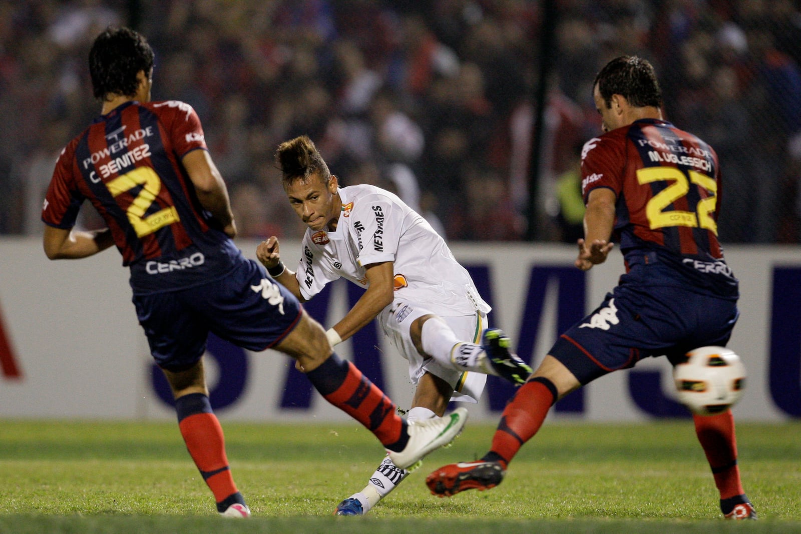 FILE - Brazil's Santos' Neymar, center, kicks the ball to score as Paraguay's Cerro Porteno's players Cesar Benitez, left, and Mariano Uglessich fail to block during a Copa Libertadores soccer game in Asuncion, Paraguay, Wednesday, June 1, 2011. (AP Photo/Cesar Olmedo, File)