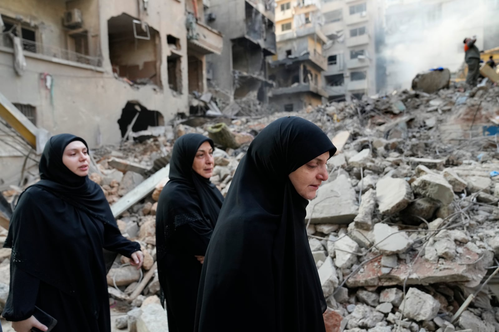 Lebanese women pass destroyed buildings at the site of Thursday's Israeli airstrike, in Beirut, Lebanon, Friday, Oct. 11, 2024. (AP Photo/Hussein Malla)