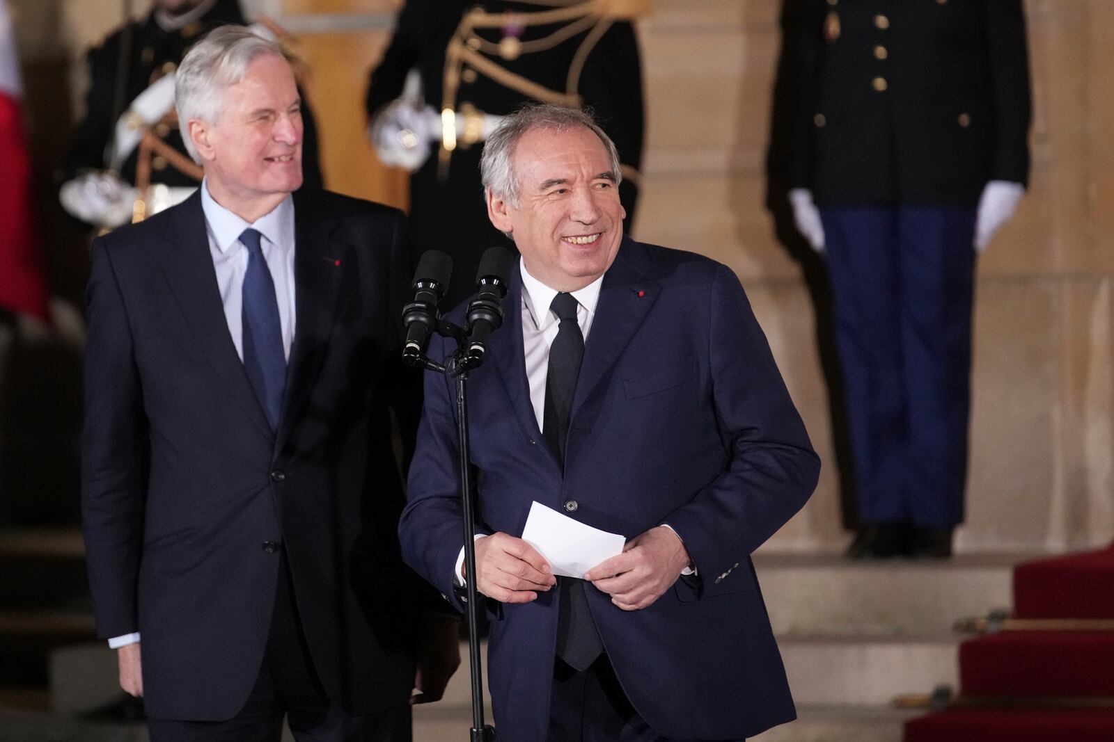 Newly named Prime Minister François Bayrou, right, and outgoing French Prime Minister Michel Barnier smile after the handover at the Prime Minister residence, Friday, Dec. 13, 2024 in Paris. (AP Photo/Christophe Ena)