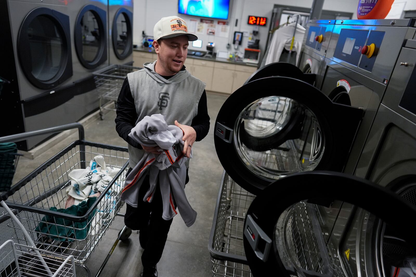 San Francisco Giants clubhouse attendant Riley Halpin loads a washing machine during baseball spring training at the team's facility, Monday, Feb. 17, 2025, in Scottsdale, Ariz. (AP Photo/Carolyn Kaster)