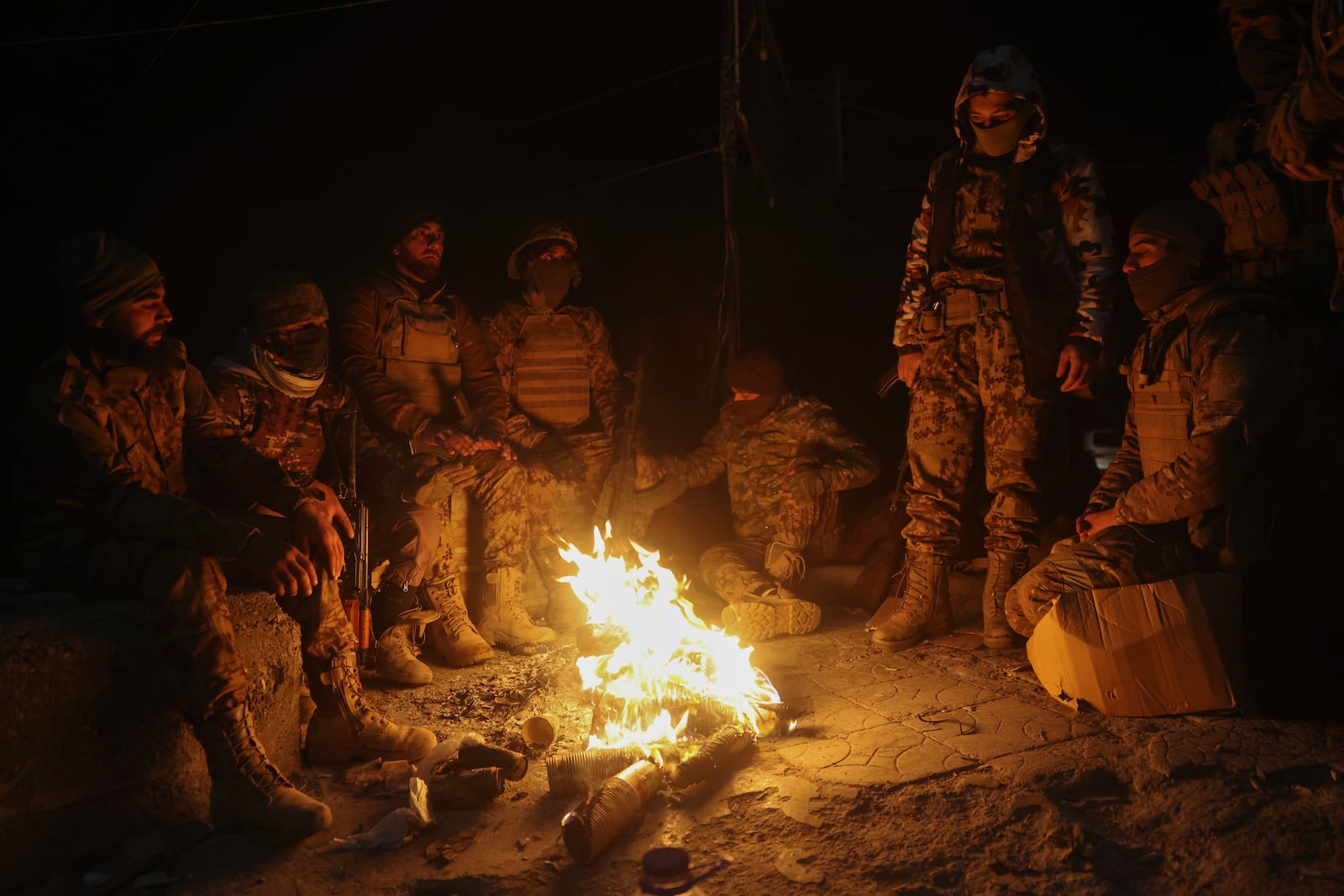 Syrian opposition fighters warm themselves by a fire in the streets of Aleppo, late Friday Nov. 29, 2024. (AP Photo/Ghaith Alsayed)