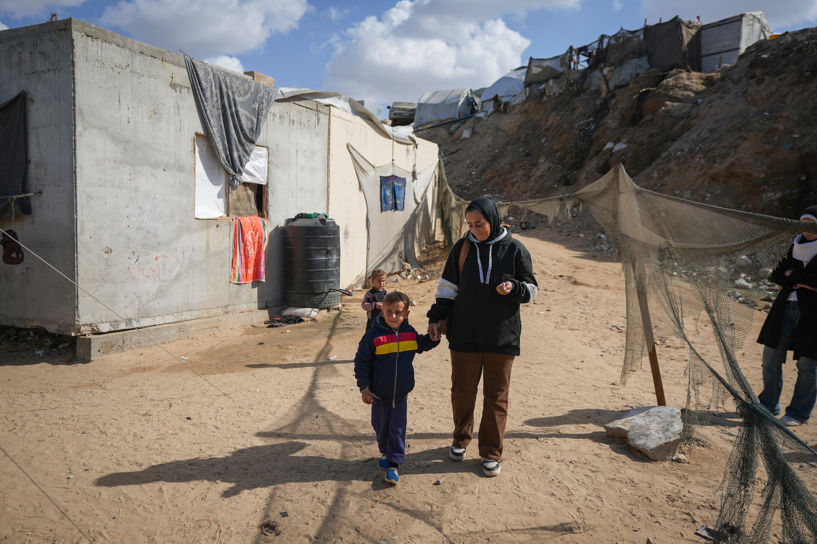 Reem Ajour walks with her son, Wael, at a camp outside Zuweida, Gaza Strip, Nov. 20, 2024. (AP Photo/Abdel Kareem Hana)