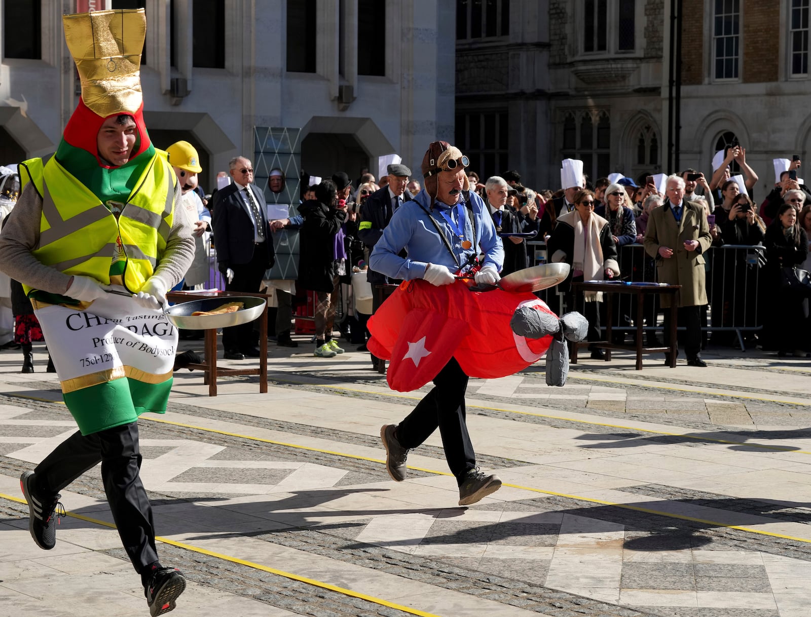 Runners in costumes compete during a traditional pancake race by livery companies at the Guildhall in London, Tuesday, March 4, 2025.(AP Photo/Frank Augstein)