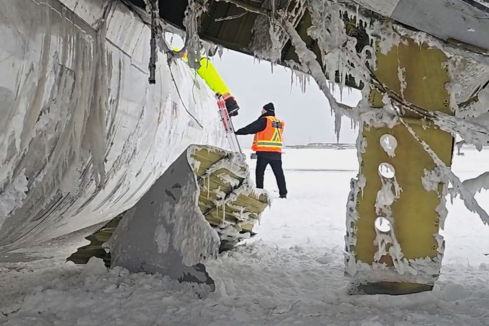 In this image provided by the National Transportation Safety Board, investigators examine the wreckage of a Delta Air Lines jet, Wednesday, Feb. 19, 2025, that burst into flames and flipped upside down as it tried to land on Feb. 17, at Toronto Pearson International Airport in Mississauga, Ontario. (National Transportation Safety Board via AP)