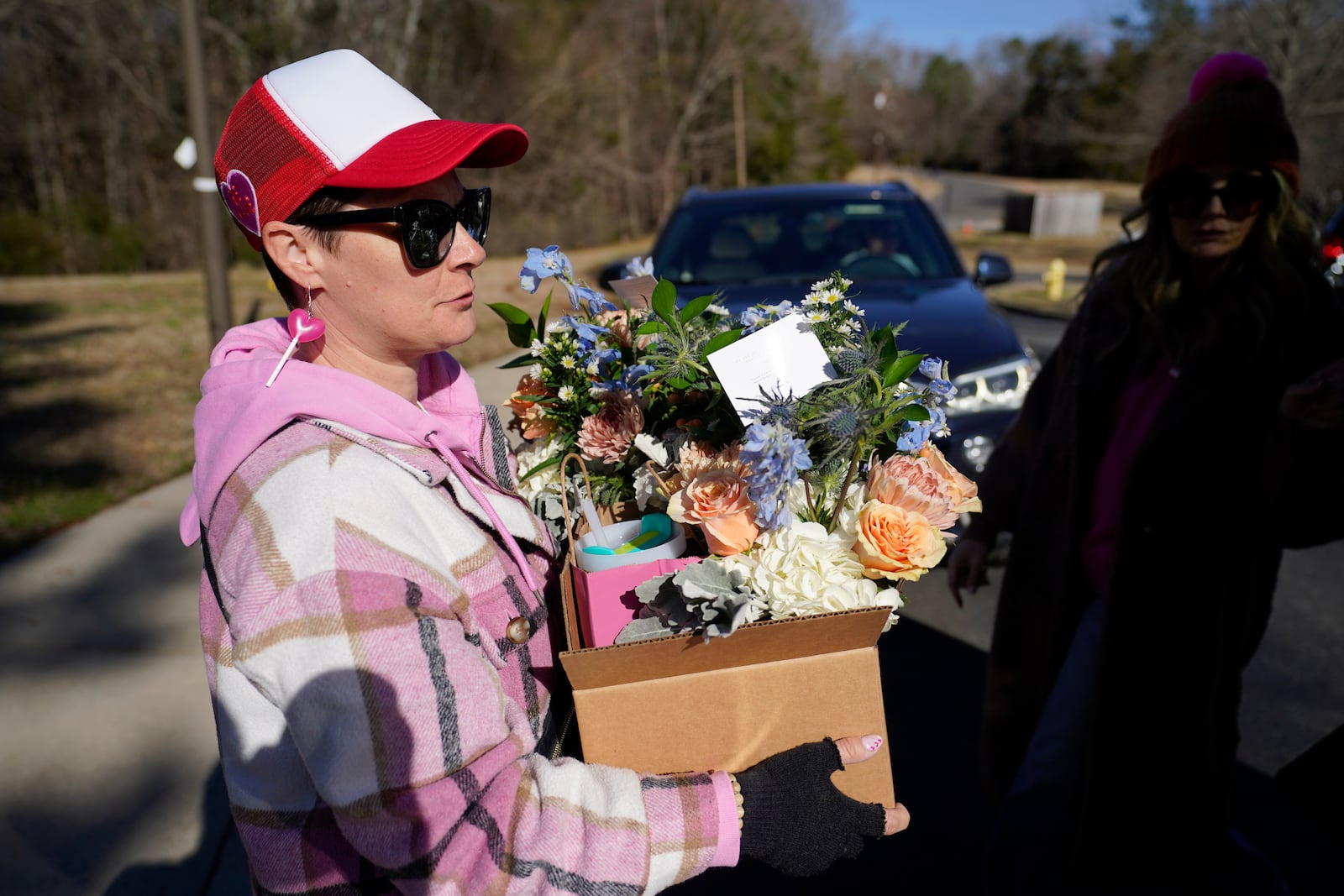 Volunteer Beth DeMarco takes a gift box to a driver for delivery during a Valentine's Day Widow Outreach Project event, Friday, Feb. 14, 2025, in Charlotte, N.C. (AP Photo/Erik Verduzco)