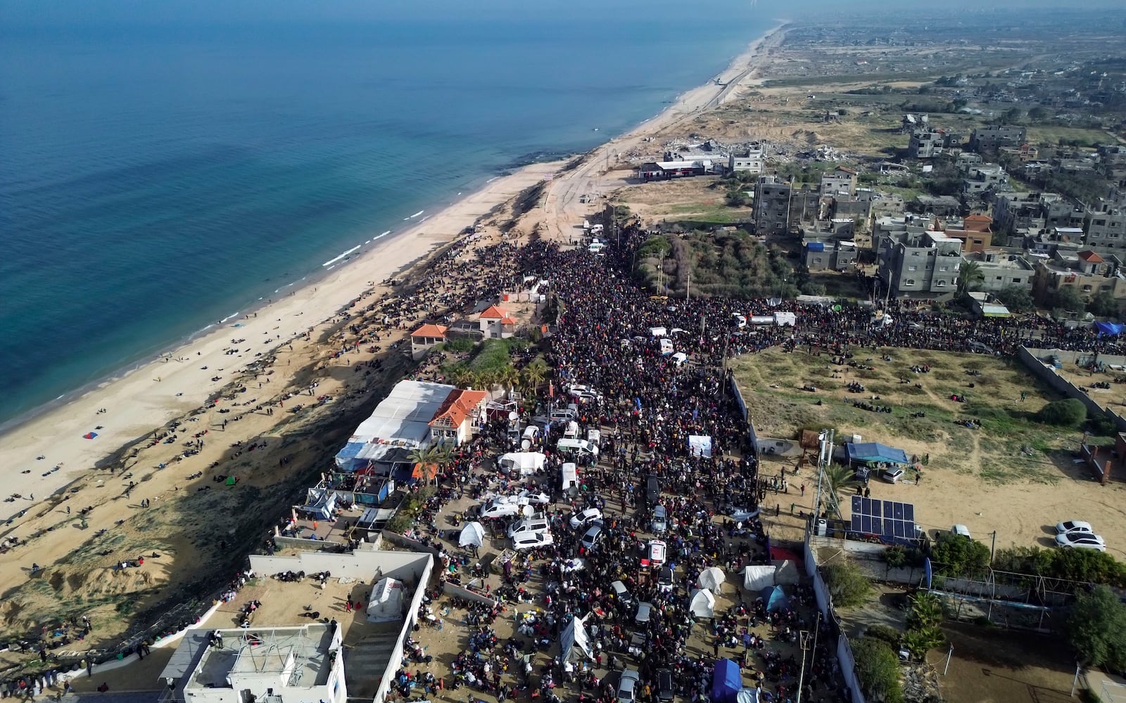 An aerial photograph taken by a drone shows displaced Palestinians gathering with their belongings near a roadblock on the al Rashid Street, as they wait to return to their homes in the northern part of the Gaza Strip, Sunday, Jan. 26, 2025, days after the ceasefire deal between Israel and Hamas came into effect. (AP Photo/Jehad Alshrafi)