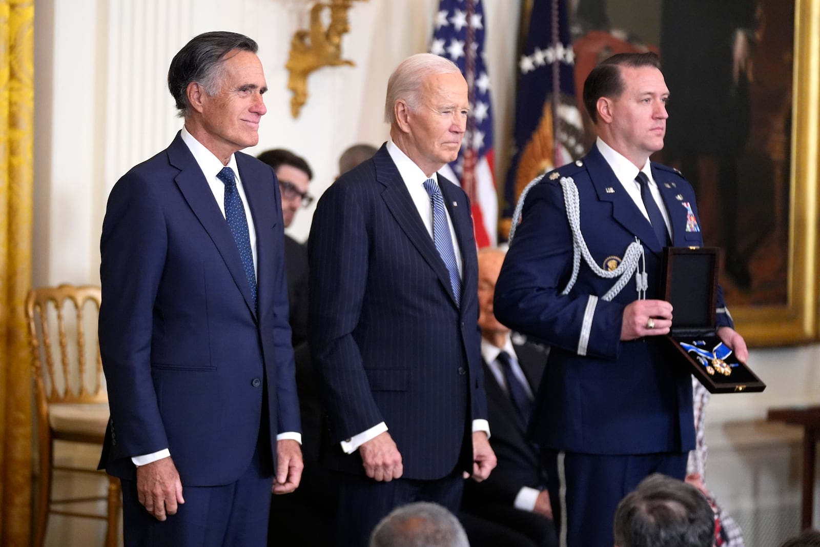 President Joe Biden, center, prepares to posthumously present the Presidential Medal of Freedom, the Nation's highest civilian honor, to former Sen. Mitt Romney, R-Utah, on behalf of his late father George Romney, in the East Room of the White House, Saturday, Jan. 4, 2025, in Washington. (AP Photo/Manuel Balce Ceneta)