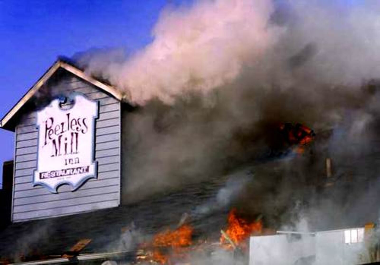 A Miamisburg fireman is on the roof of the Peerless Mill Inn, a restaurant in Miamisburg. The restaurant was consumed by fire Friday, January 24, 2003.