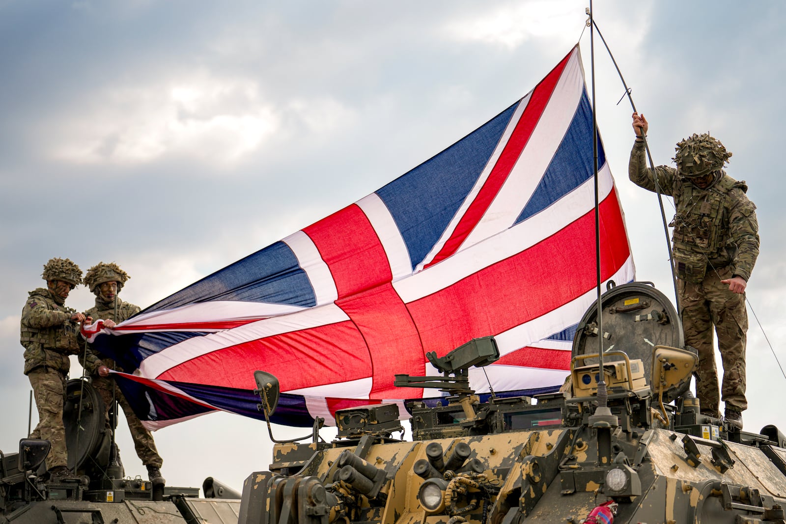 British servicemen unfurl the Union Jack flag before the start of the Steadfast Dart 2025 exercise, involving some 10,000 troops in three different countries from nine nations and represent the largest NATO operation planned this year, at a training range in Smardan, eastern Romania, Wednesday, Feb. 19, 2025. (AP Photo/Vadim Ghirda)