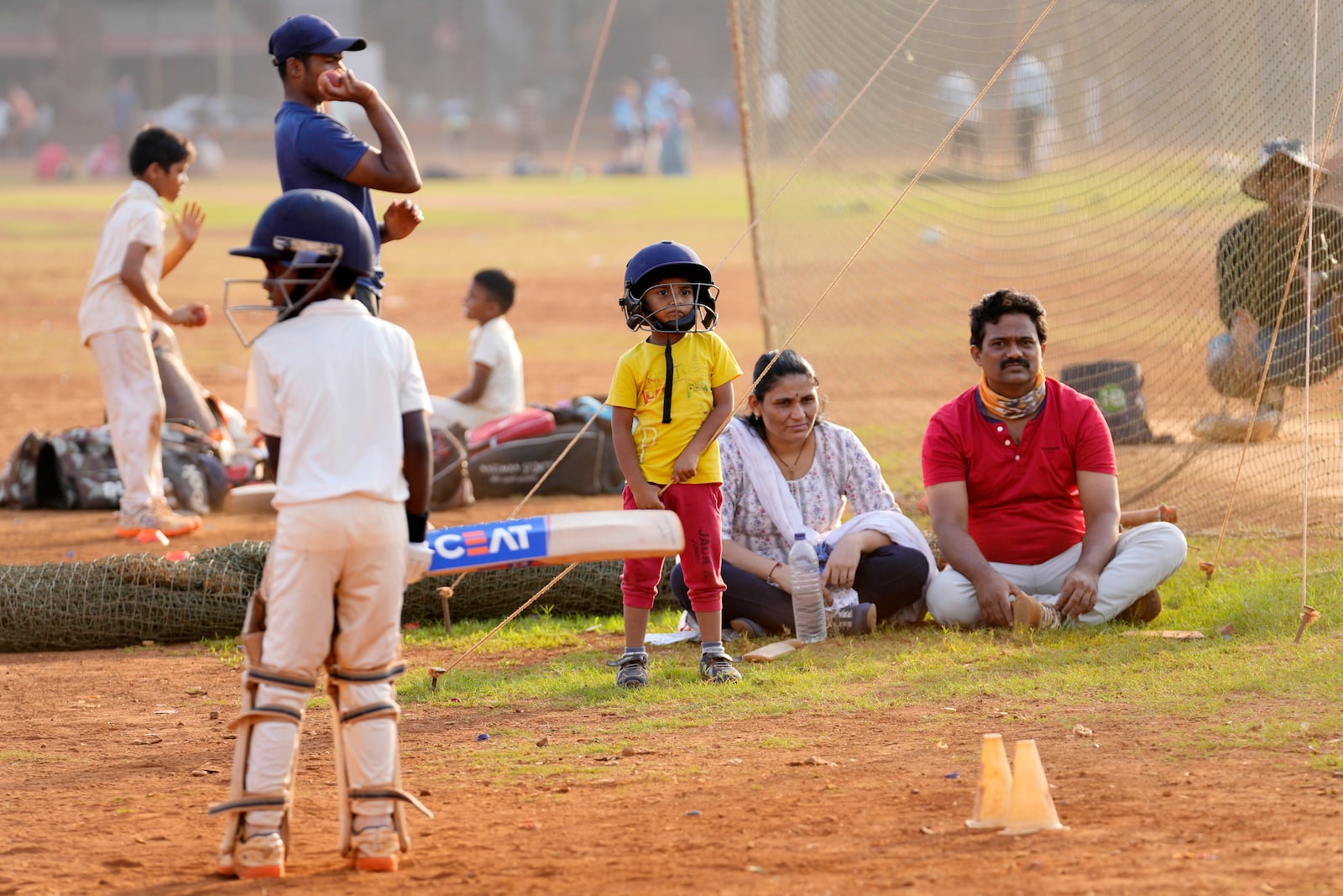 An Indian family watches their children during a cricket coaching camp in Mumbai, India, Friday, Feb. 21, 2025. (AP Photo/Rajanish Kakade)