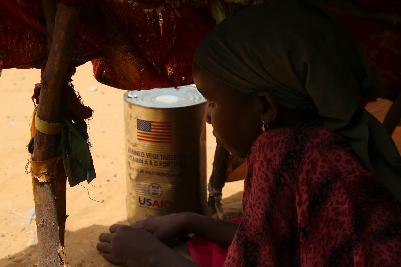 A Somali internally-displaced person (IDP) child looks out from her family's makeshift home in Maslah camp on the outskirts of Mogadishu, Somalia Wednesday, Feb. 5, 2025. (AP Photo/Farah Abdi Warsameh)