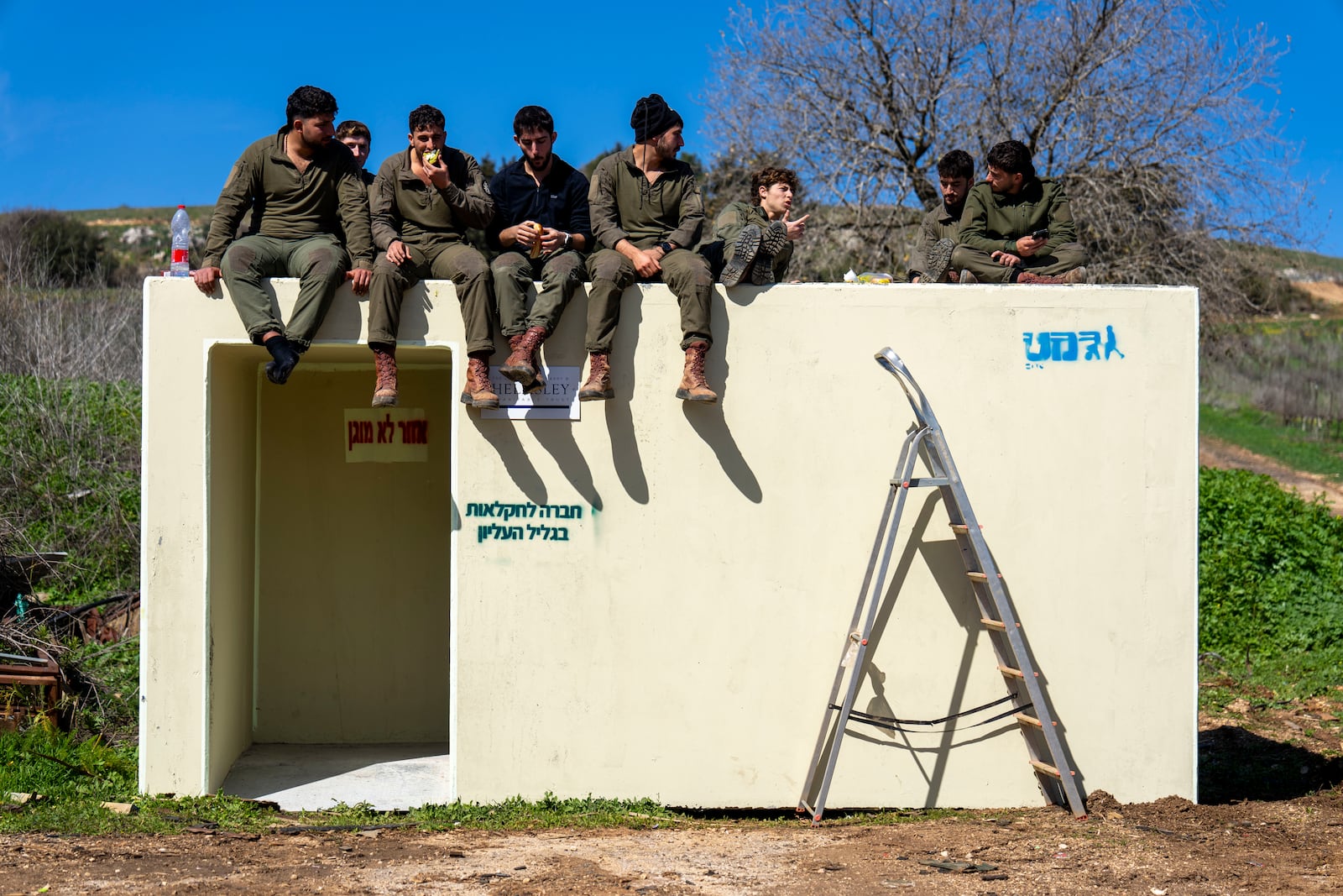 Israeli soldiers sit on a bomb shelter in northern Israel after Israeli forces withdrew from border villages in southern Lebanon, Tuesday, Feb. 18, 2025. (AP Photo/Ariel Schalit)