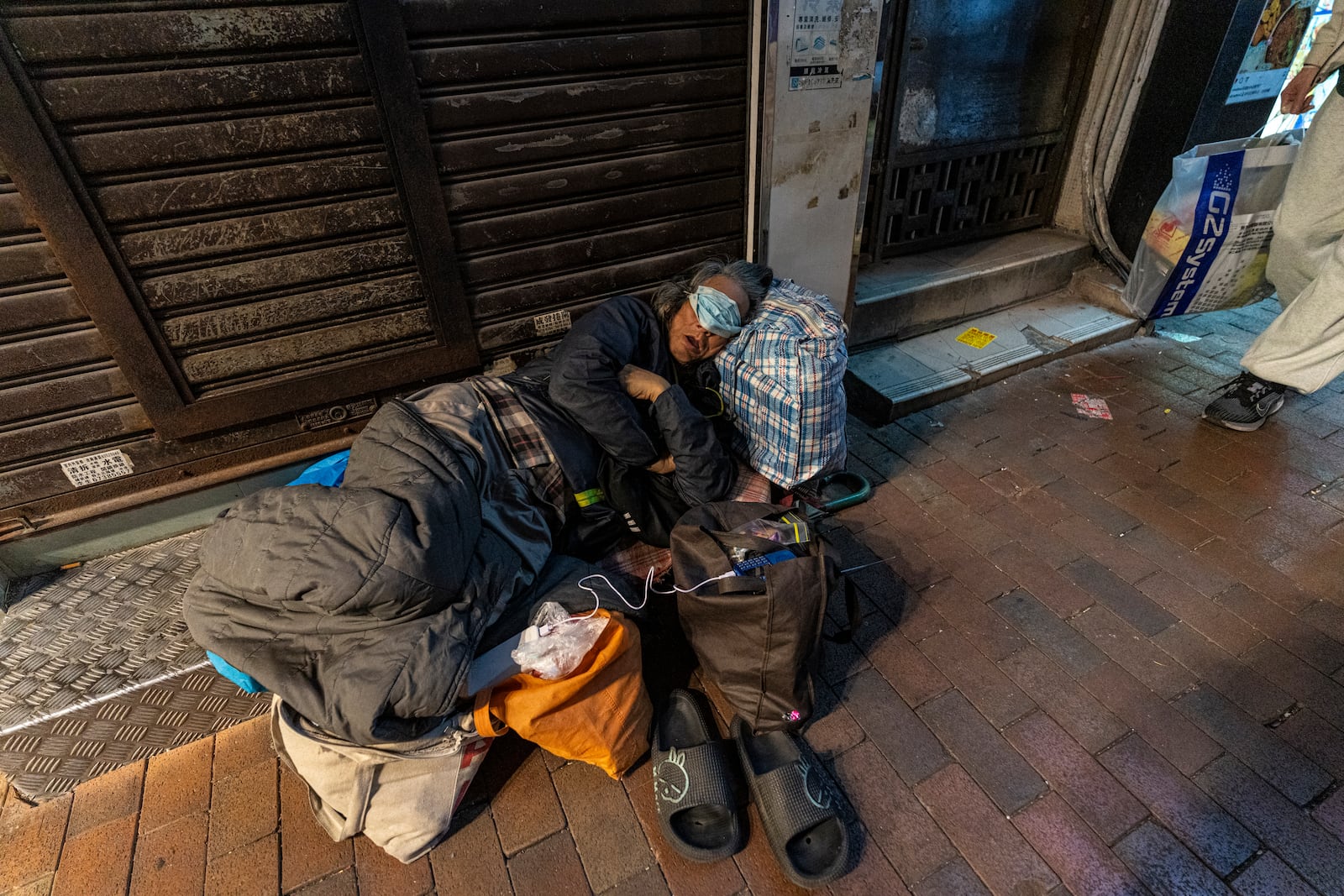 A homeless person sleeps on a street in Sham Shui Po district of Hong Kong, on Feb. 6, 2025. (AP Photo/Chan Long Hei)