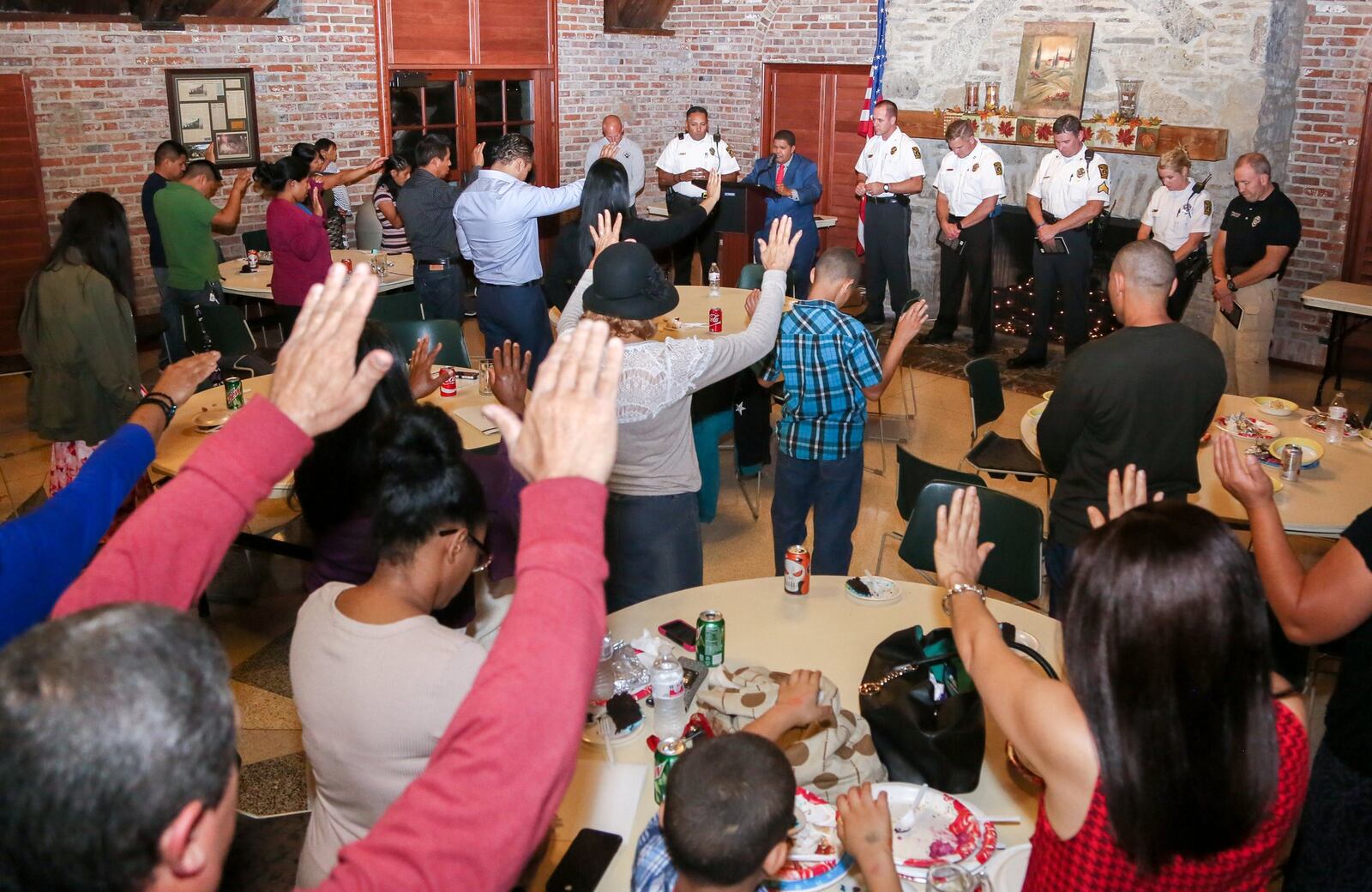 Hamilton Police Chief Craig Bucheit and other officers stand as the graduating class of the Hamilton Police Department’s Hispanic Police Academy and their families pray for them during a celebration at the Michael Colligan Lodge in Veterans Park, Thursday, Oct. 13, 2016. Eighteen citizens were recognized for completing the program. GREG LYNCH / STAFF