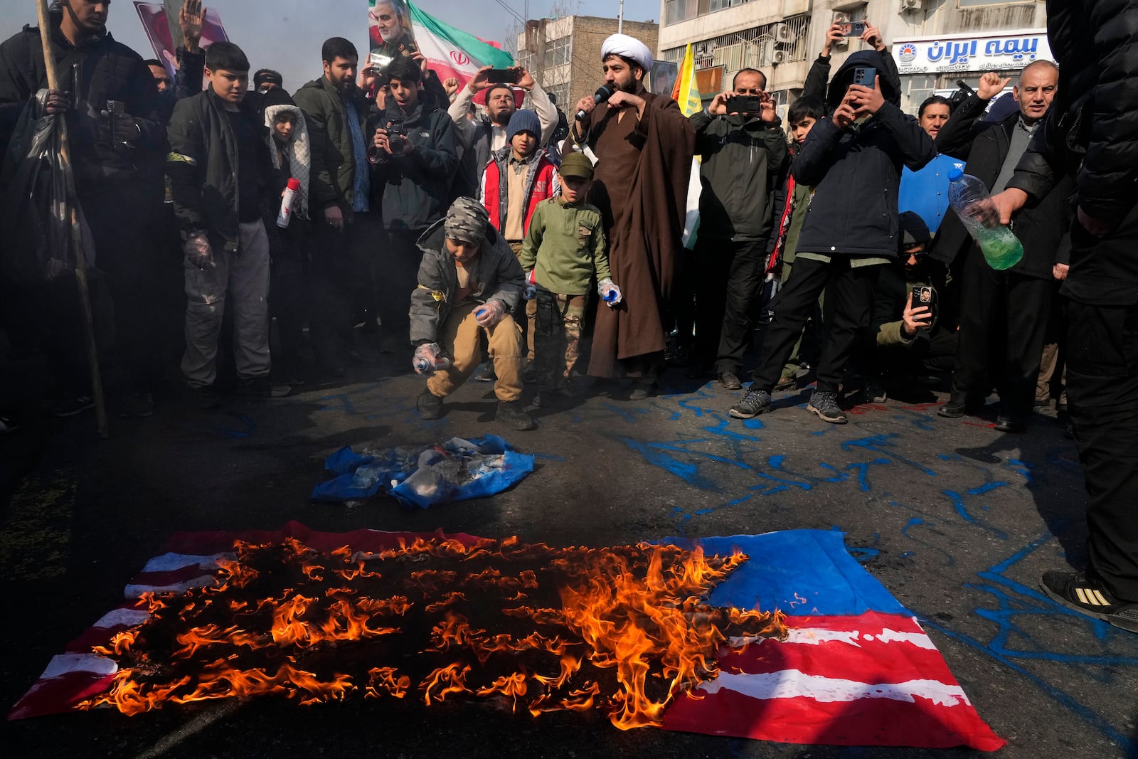 Iranian demonstrators burn representations of the U.S. and Israeli flags during a rally commemorating anniversary of Iran's 1979 Islamic Revolution that toppled the late pro-U.S. Shah Mohammad Reza Pahlavi and brought Islamic clerics to power, in Tehran, Iran, Monday, Feb. 10, 2025. (AP Photo/Vahid Salemi)