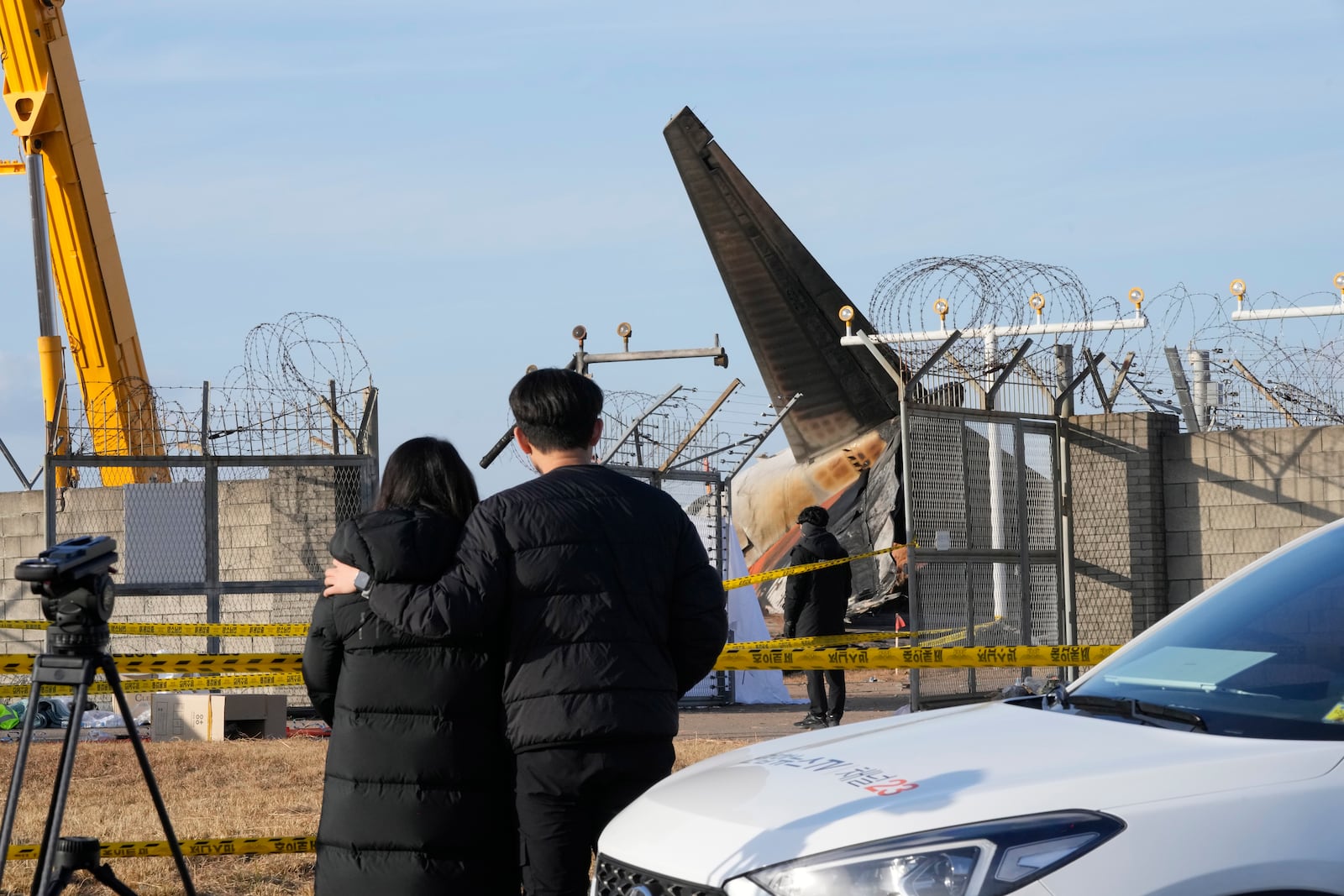 Mourners watch the site of a plane fire from outside of Muan International Airport in Muan, South Korea, Monday, Dec. 30, 2024. (AP Photo/Ahn Young-joon)