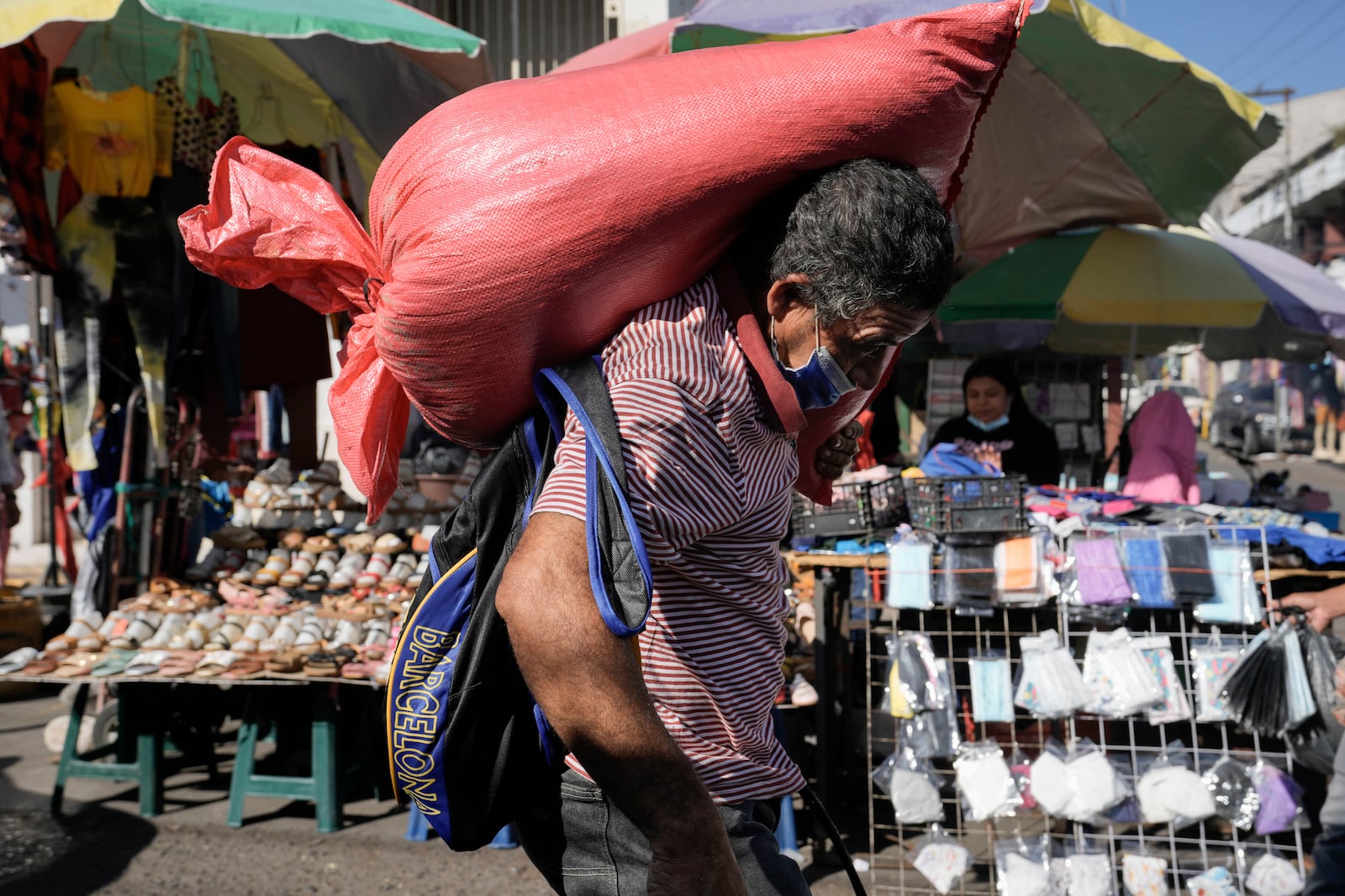 FILE - A man carries a sack of corn through the Comayaguela market on the outskirts of Tegucigalpa, days after general elections in Honduras, Nov. 30, 2021. (AP Photo/Moises Castillo, File)