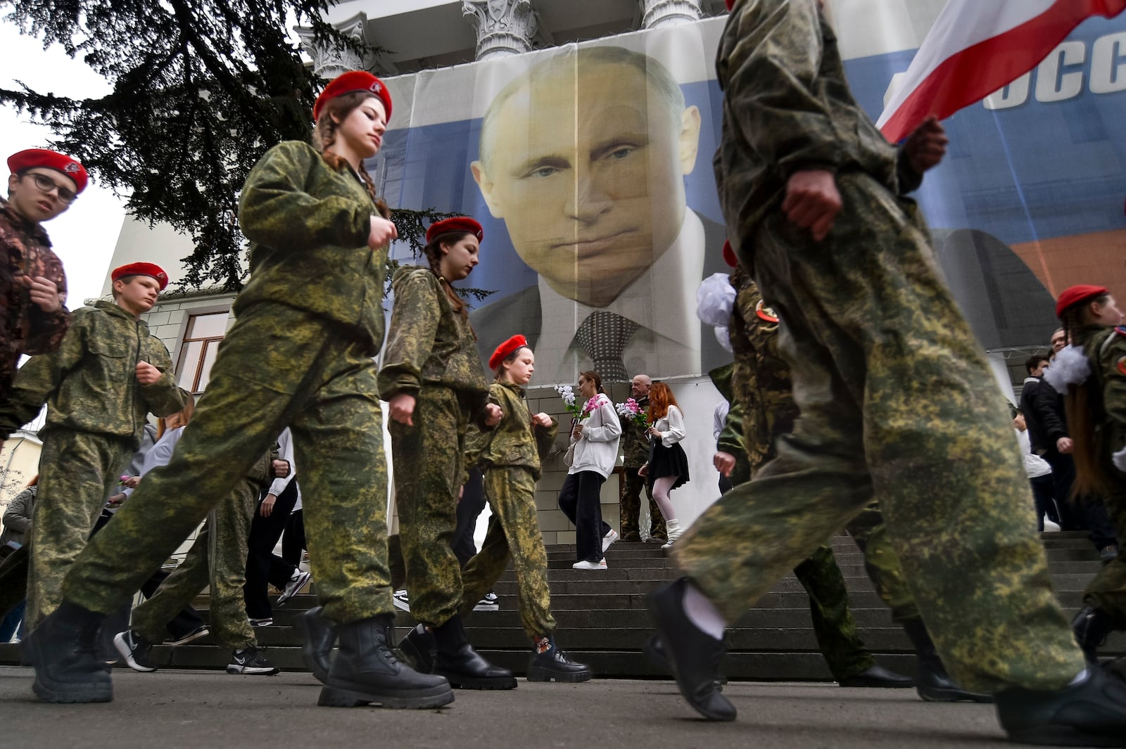 FILE - Youths mark the ninth anniversary of the annexation of Crimea from Ukraine with a banner reading, "Russia doesn't start wars, it ends them," next to an image of Russian President Vladimir Putin in Yalta, Crimea, on March 17, 2023. (AP Photo, File)