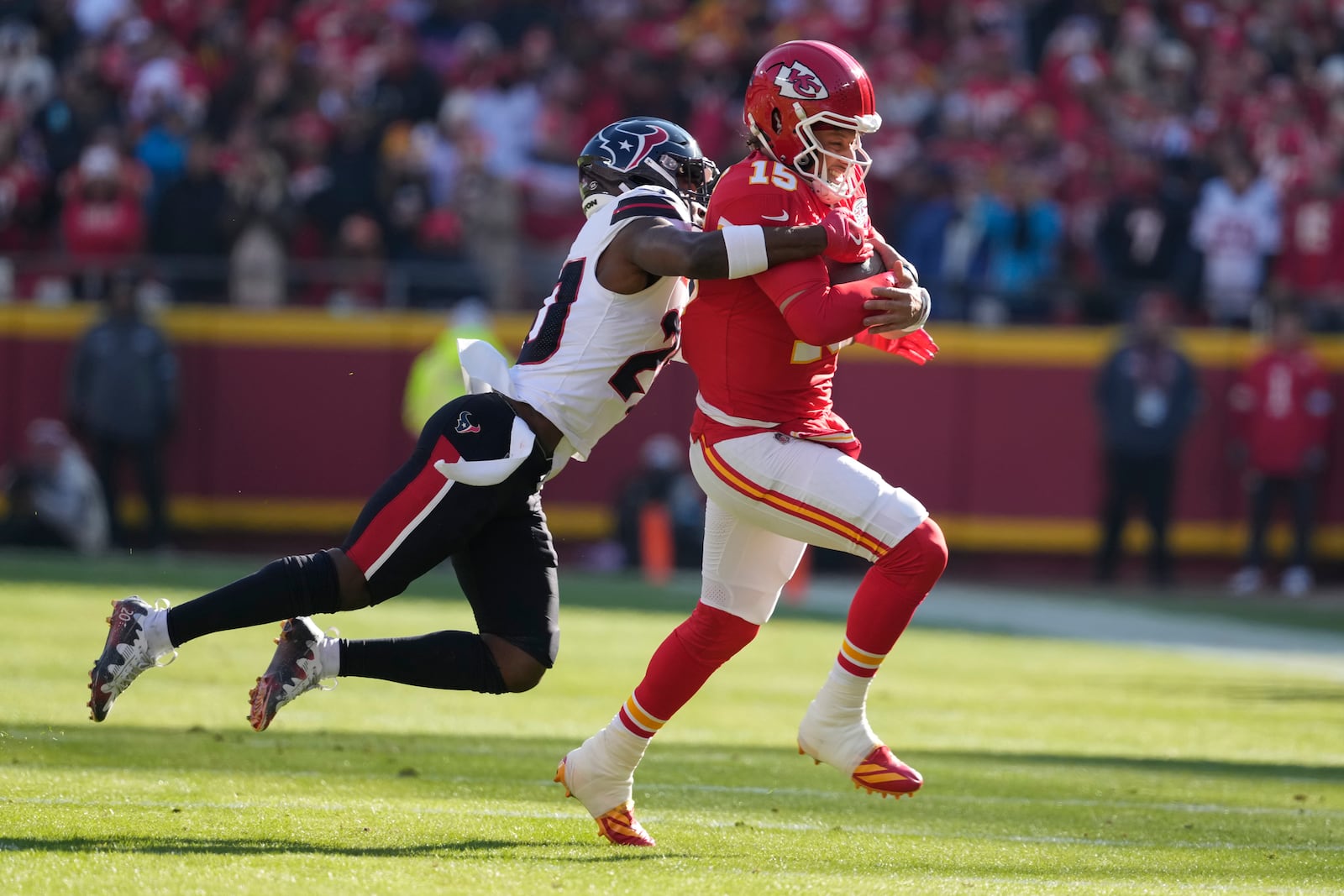 Kansas City Chiefs quarterback Patrick Mahomes, right, is pulled down by Houston Texans safety Jimmie Ward during the first half of an NFL football game Saturday, Dec. 21, 2024, in Kansas City, Mo. (AP Photo/Ed Zurga)