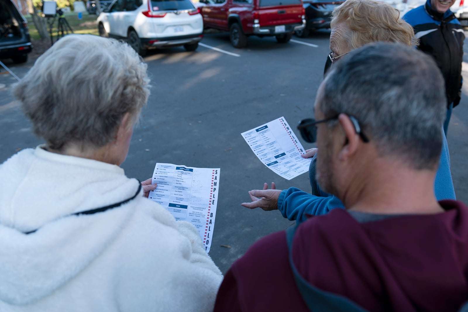 Voters discuss sample ballots while waiting in line to cast their early in-person vote, Thursday, Oct. 17, 2024, in Asheville, N.C. (AP Photo/Stephanie Scarbrough)