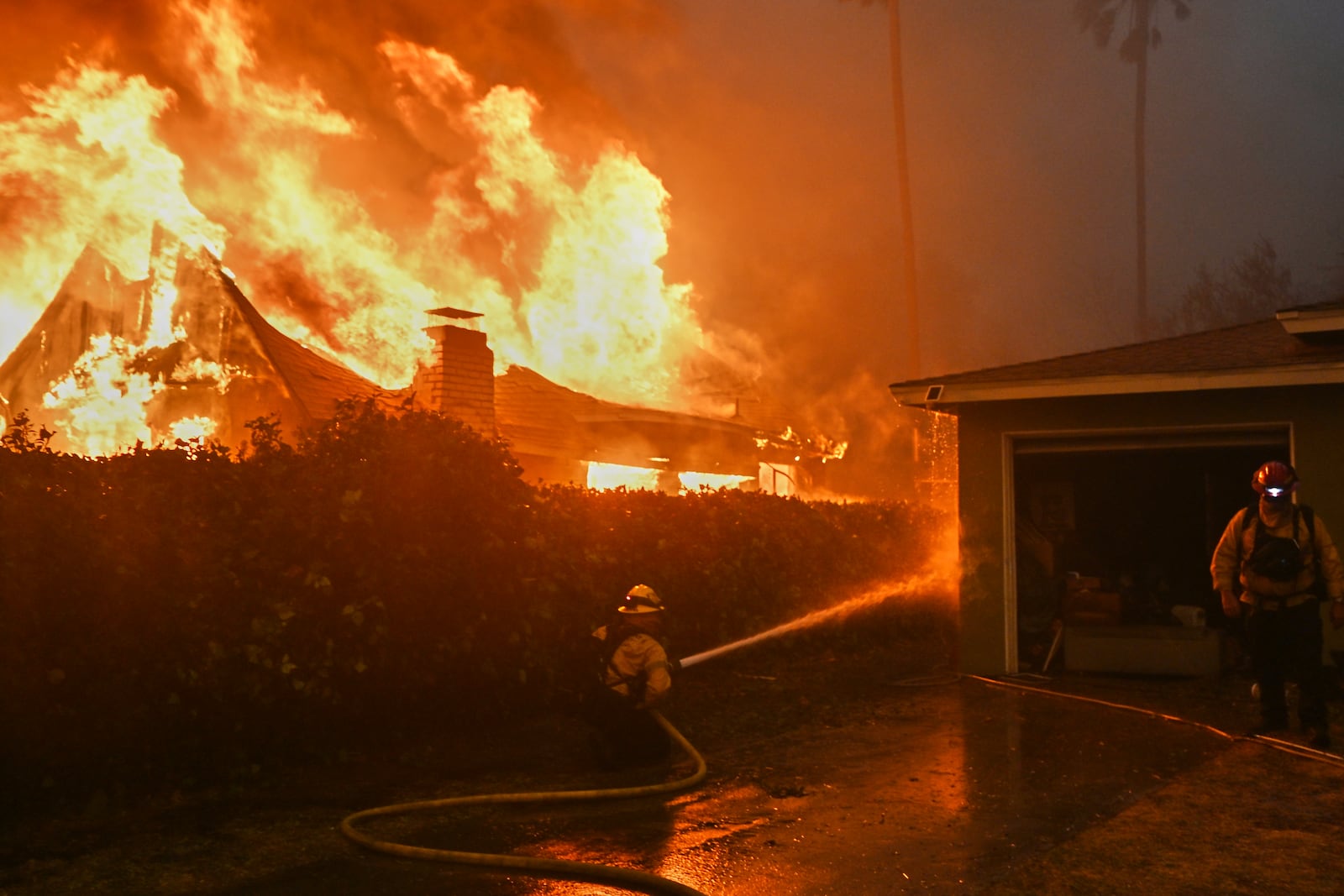 Fire crews battle the Eaton Fire next to a fully engulfed residence, Wednesday, Jan. 8, 2025 in Altadena, Calif. (AP Photo/Nic Coury)