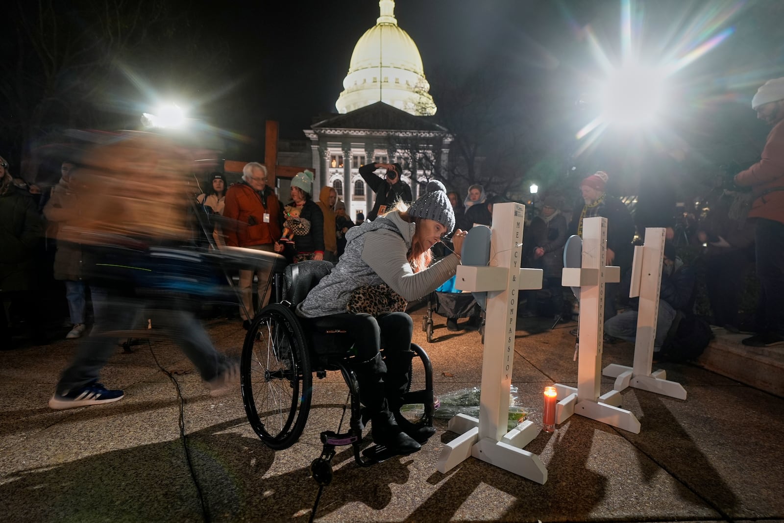 A supporter signs a cross during a candlelight vigil Tuesday, Dec. 17, 2024, outside the Wisconsin Capitol in Madison, Wis., following a shooting at the Abundant Life Christian School on Monday, Dec. 16. (AP Photo/Morry Gash)