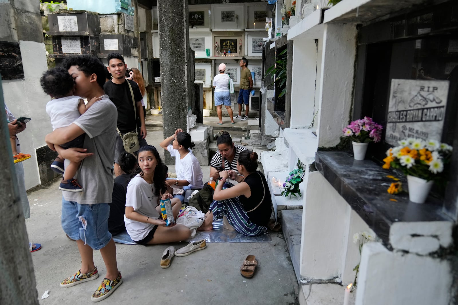 A family gathers in front of the tomb of their loved one at Manila's North Cemetery, Philippines as the nation observes All Saints Day on Friday, Nov. 1, 2024. (AP Photo/Aaron Favila)