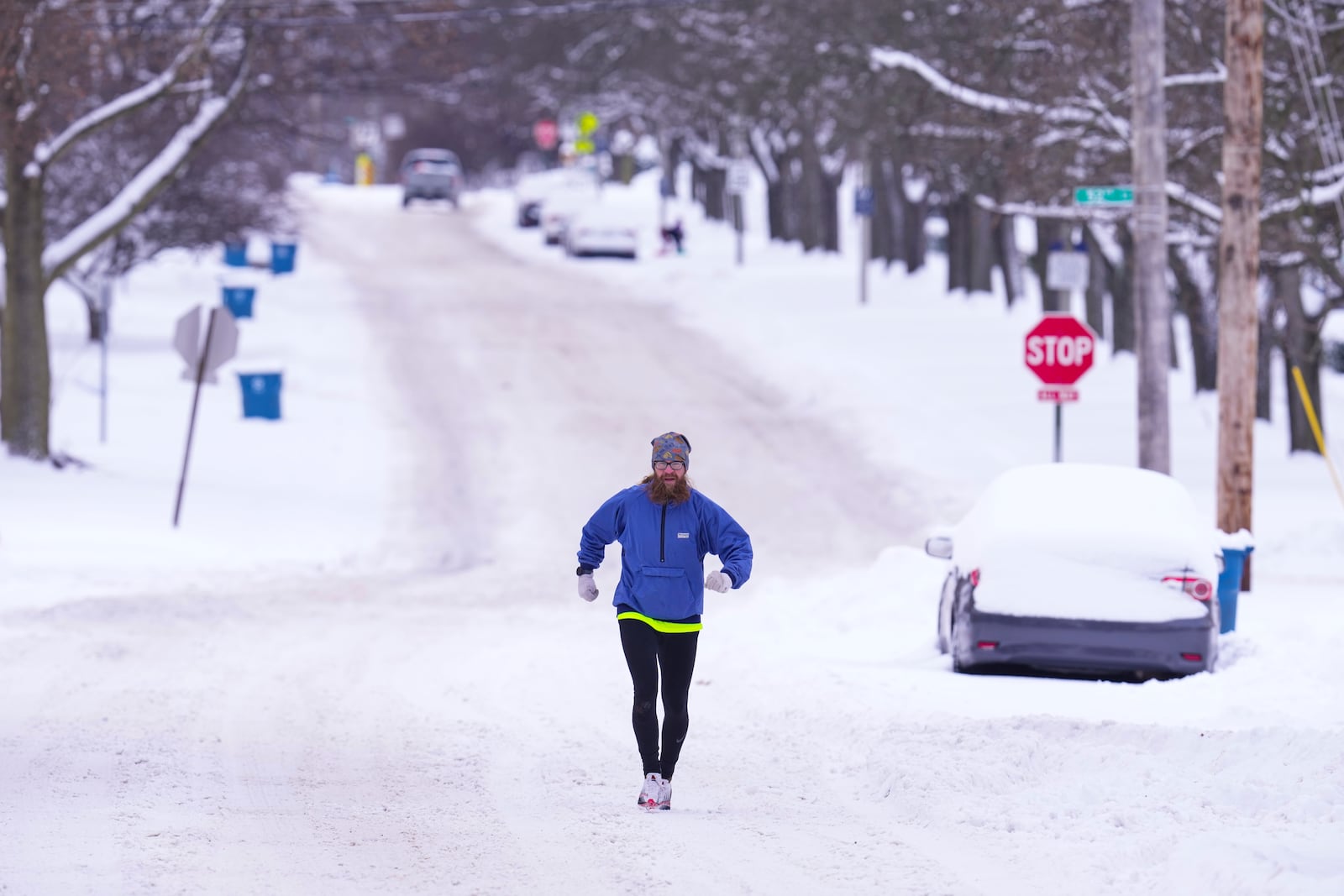 A runner makes his way through a snow-covered street in Indianapolis, Monday, Jan. 6, 2025. (AP Photo/Michael Conroy)