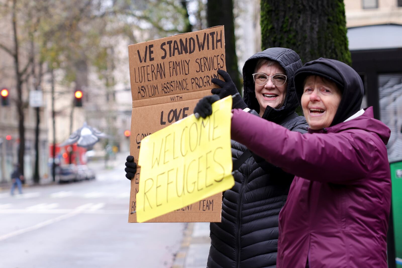 People hold signs at passing cars during a rally outside the U.S District Court before a federal judge blocked President Donald Trump's effort to halt the nation's refugee admissions system, Tuesday, Feb. 25, 2025 in Seattle. (AP Photo/Ryan Sun)