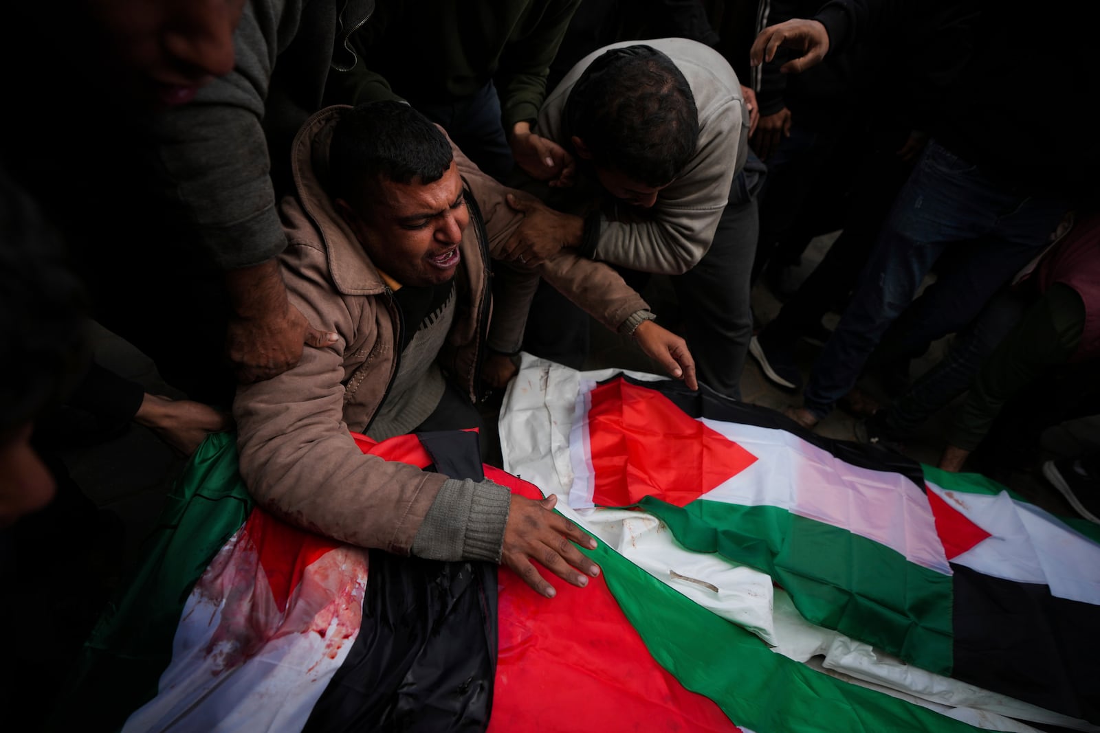 Palestinians mourn their relatives killed in the Israeli bombardment of the Gaza Strip, at Al-Aqsa Martyrs Hospital in Deir al-Balah, Sunday, Jan. 5, 2025. (AP Photo/Abdel Kareem Hana)