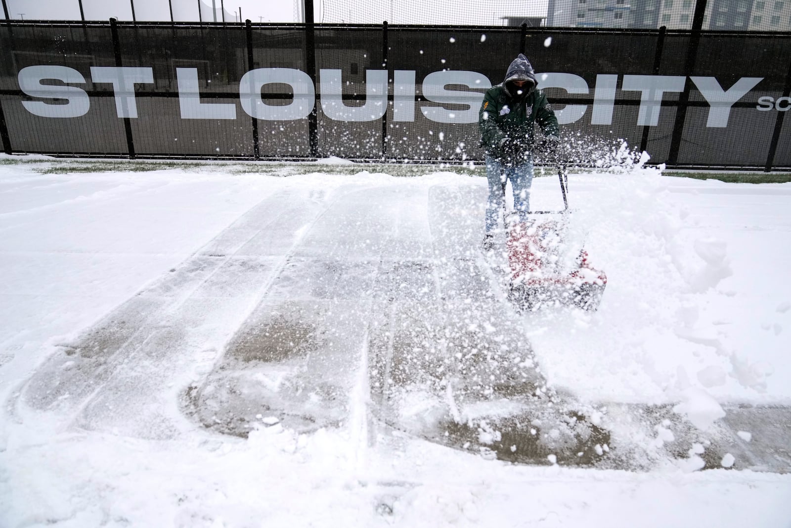 Andre Dresino uses a snow blower to clear a sidewalk Sunday, Jan. 5, 2025, in St. Louis. (AP Photo/Jeff Roberson)