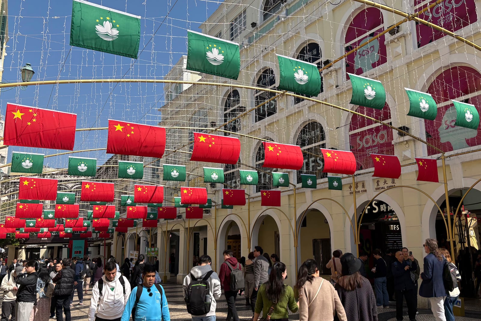 Tourists walk past a street decorated with Chinese national flags and Macao regional flags in Macao on Dec. 13, 2024. (AP Photo/Kanis Leung)