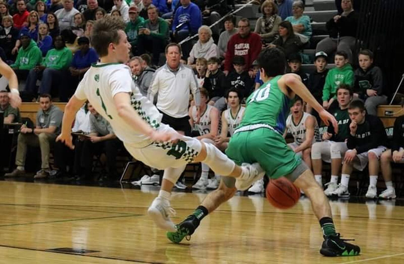 Badin’s Joseph Walsh (1) gets knocked backward while defending Chaminade Julienne’s Jack Nauseef (10) during Friday night’s game at Mulcahey Gym in Hamilton. CJ won 58-54. CONTRIBUTED PHOTO BY TERRI ADAMS