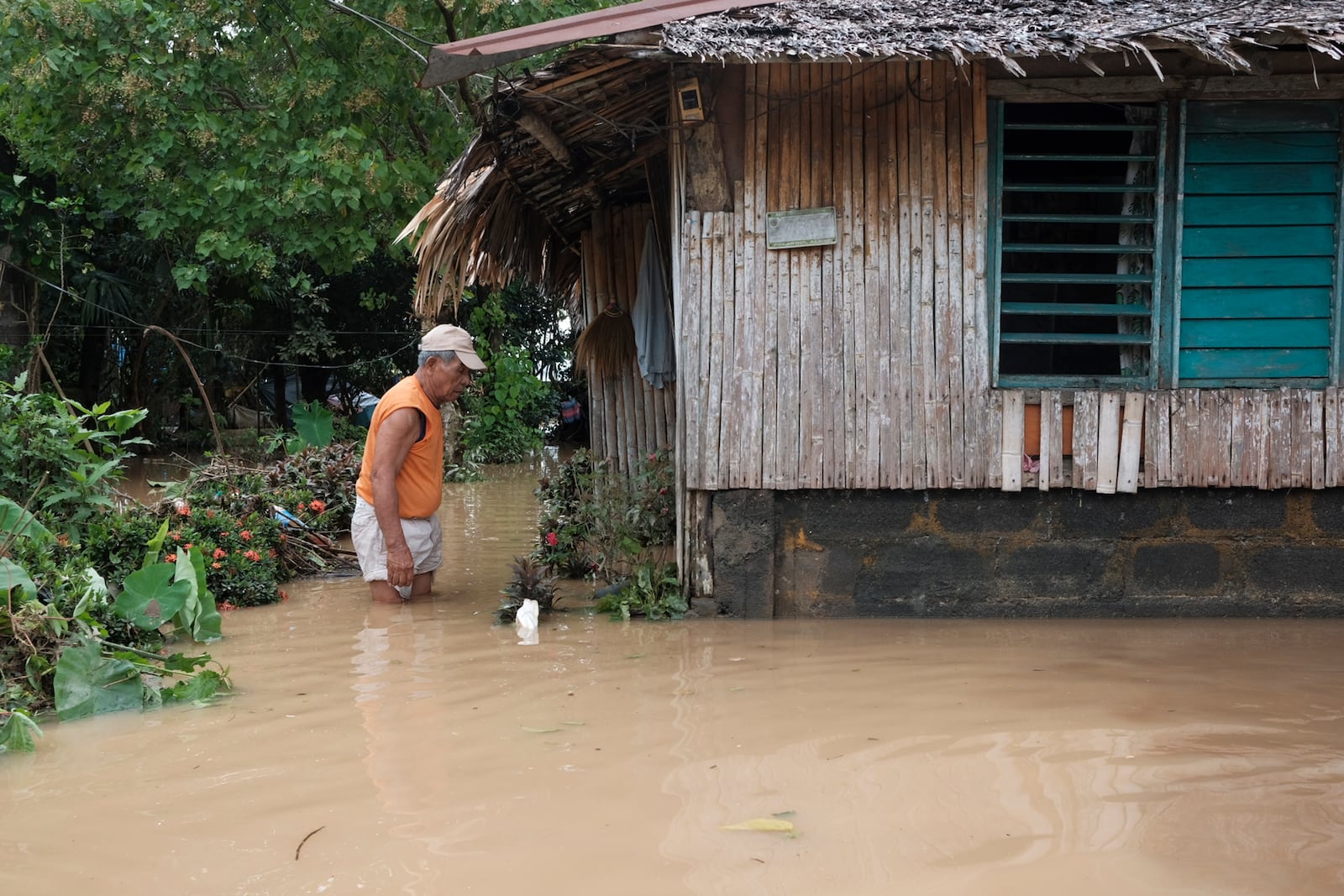 A man wades in floods outside his house caused by Tropical Trami, locally named Kristine, in Polangui, Albay province, Philippines on Oct. 23, 2024. (AP Photo/John Michael Magdasoc)