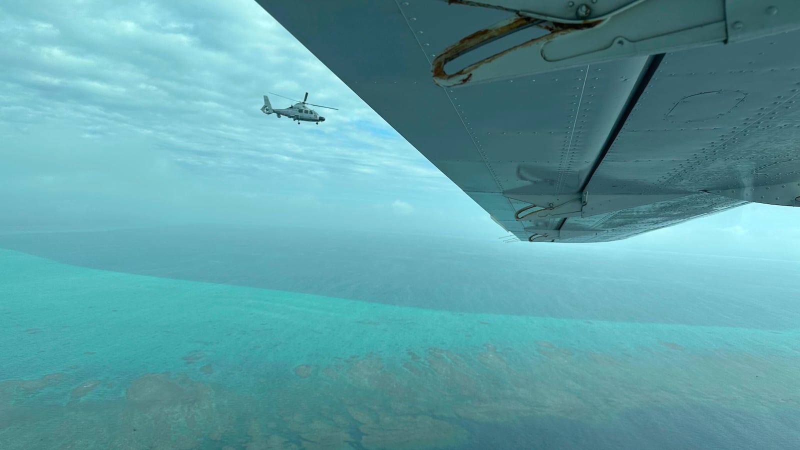 A Chinese military helicopter flies close to a Philippine Bureau of Fisheries and Aquatic (BFAR) aircraft above Scarborough shoal on Tuesday, Feb. 18, 2025. (AP Photo/Joeal Calupitan)