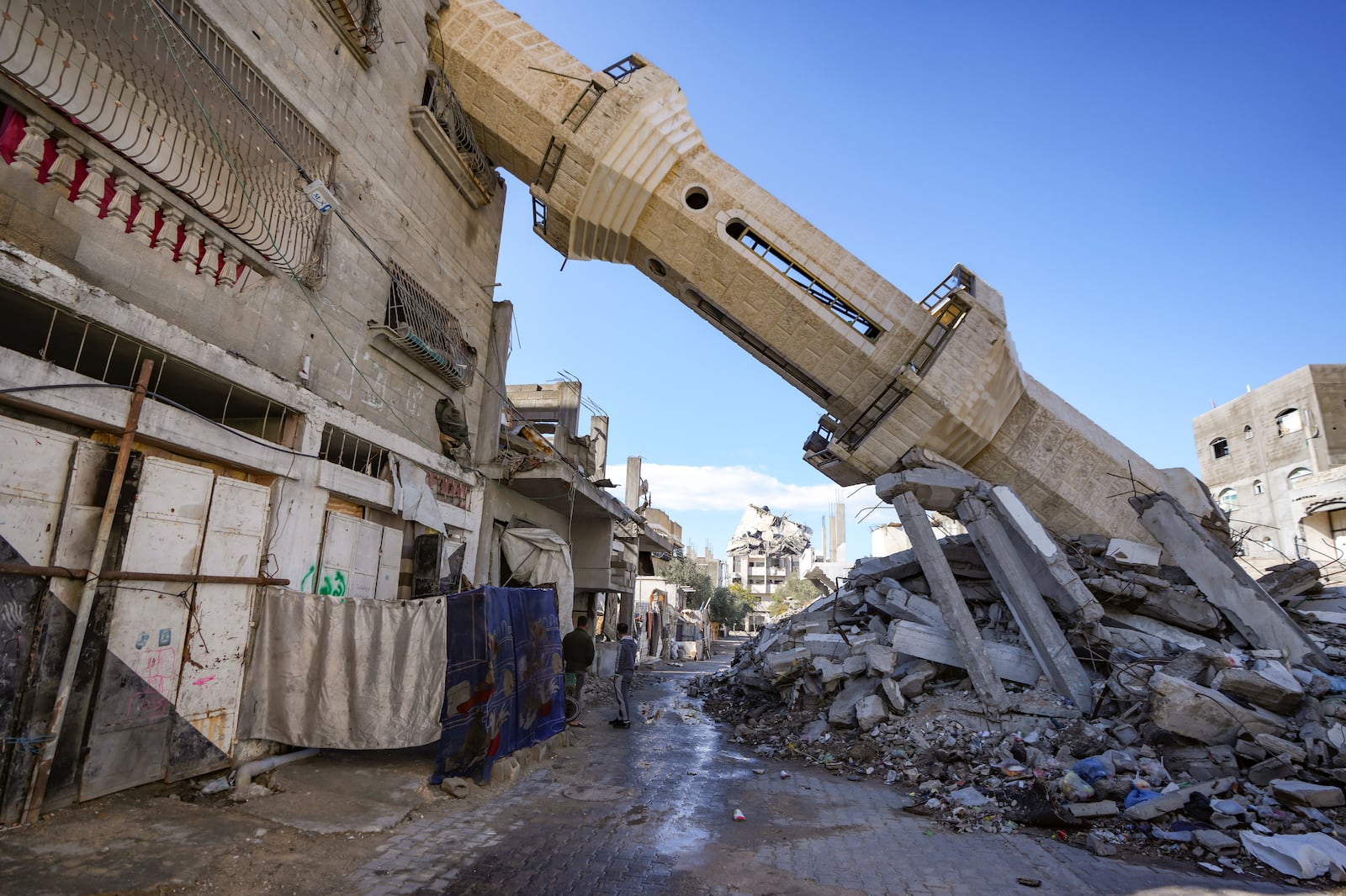 Palestinians walk past a mosque destroyed by the Israeli airstrikes in Nuseirat, Gaza Strip, Friday, Jan. 24, 2025, days after the ceasefire deal between Israel and Hamas came into effect. (AP Photo/Abdel Kareem Hana)