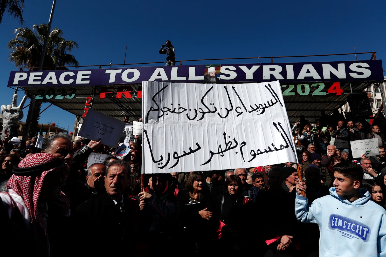 Syrian Druze hold up a placard in Arabic reads "Sweida will not be your poisoned dagger in Syria's back." as stage a demonstration against Israeli incursions into Syrian territory in the southern province of Sweida, Syria, Tuesday, Feb. 25, 2025. (AP Photo/Omar Sanadiki)