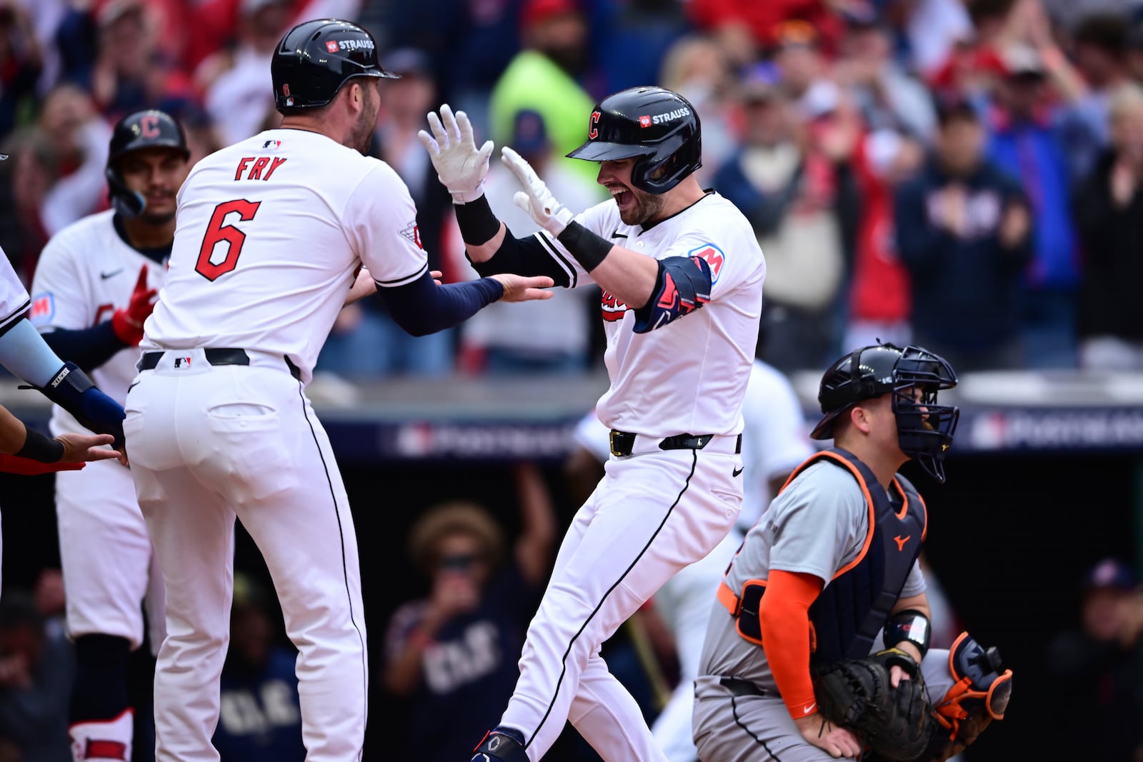 Cleveland Guardians' Lane Thomas, center, is greeted by teammate David Fry, left, behind Detroit Tigers catcher Jake Rogers, right, after hitting a grand slam in the fifth inning during Game 5 of baseball's American League Division Series, Saturday, Oct. 12, 2024, in Cleveland. (AP Photo/David Dermer)