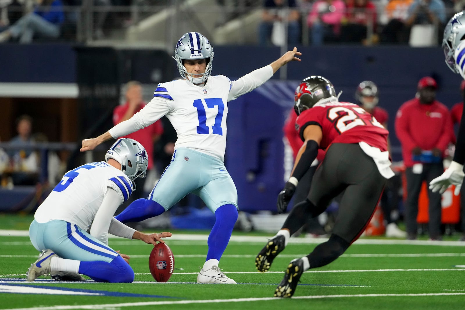 Dallas Cowboys place kicker Brandon Aubrey (17) kicks a field goal as punter Bryan Anger (5) holds, under pressure from Tampa Bay Buccaneers cornerback Zyon McCollum (27) in the first half of an NFL football game in Arlington, Texas, Sunday, Dec. 22, 2024. (AP Photo/Jeffrey McWhorter)