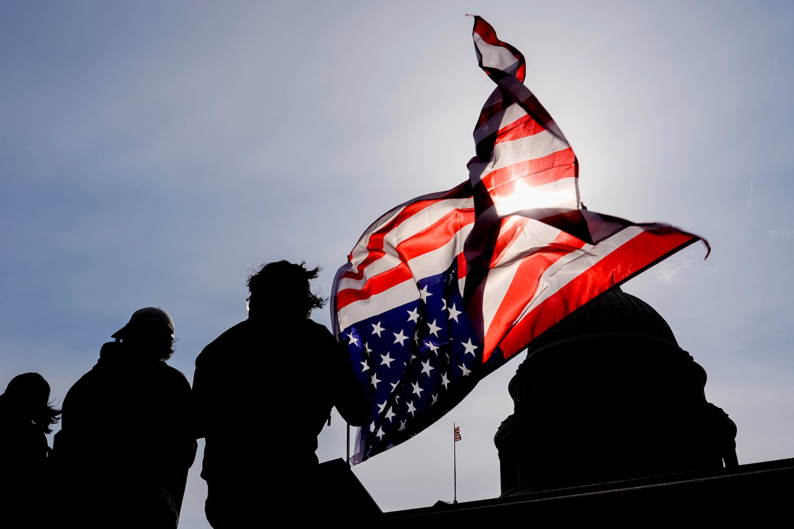 A protester waves an upside down American flag in front of the Capitol, Tuesday, March 4, 2025, in Washington. (AP Photo/Julia Demaree Nikhinson)