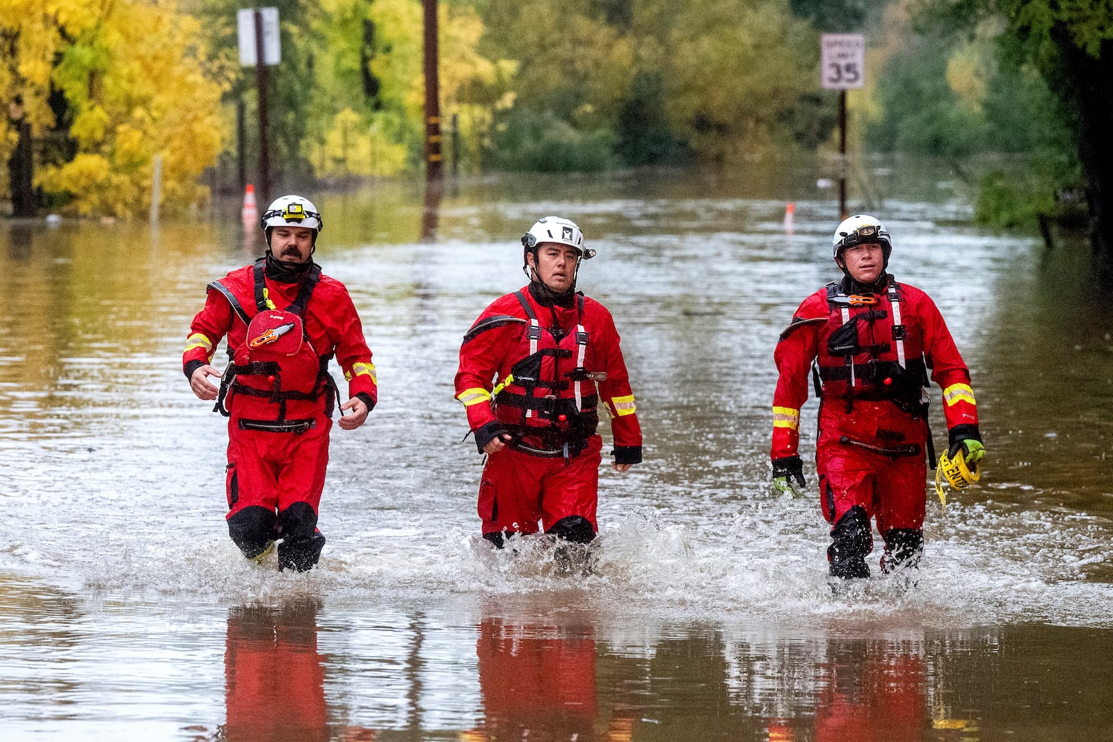 Firefighters walk through floodwaters while responding to a rescue call in unincorporated Sonoma County, Calif., on Friday, Nov. 22, 2024. (AP Photo/Noah Berger)