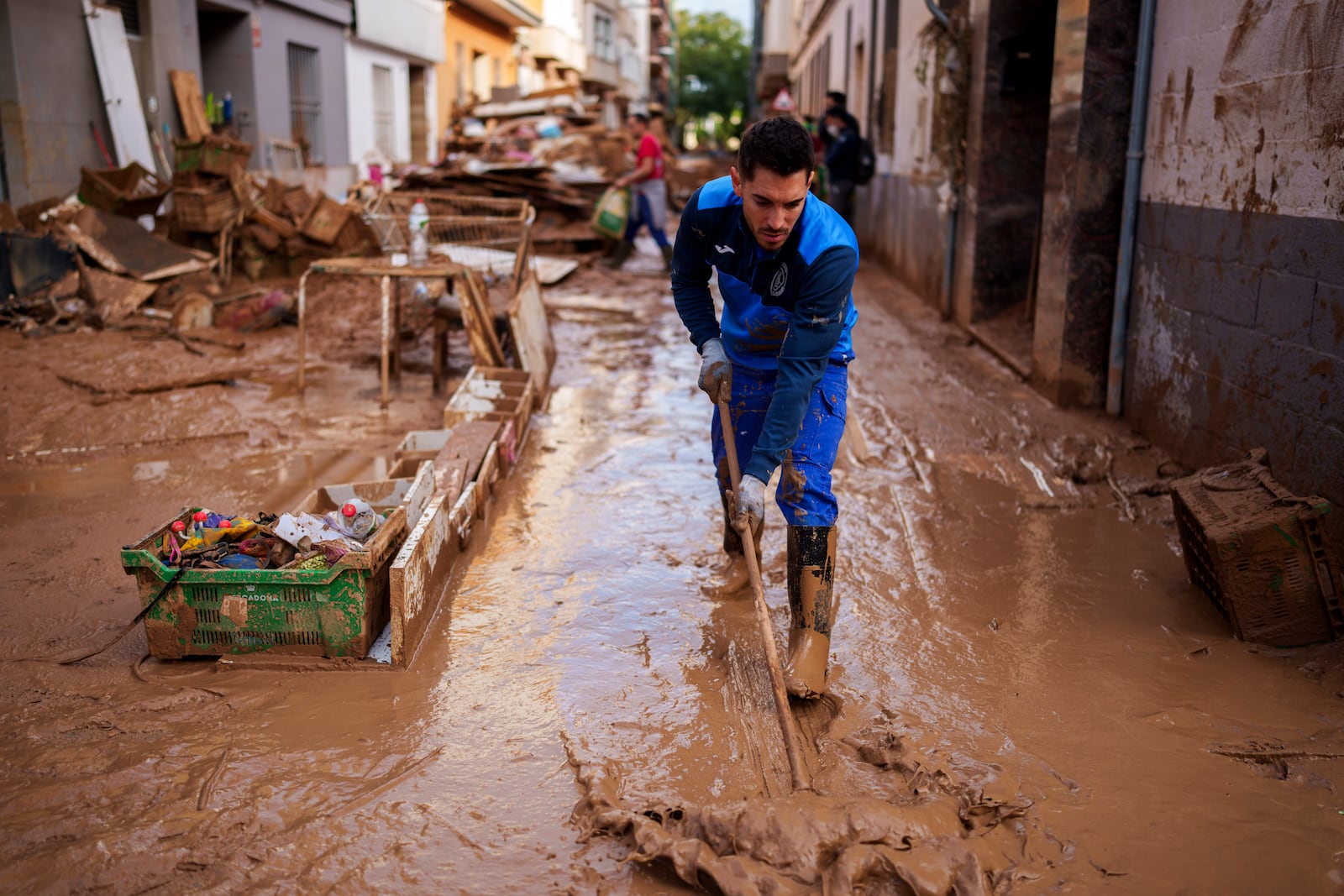 A man cleans the street of mud in an area affected by floods in Valencia, Spain, Saturday, Nov. 2, 2024. (AP Photo/Manu Fernandez)