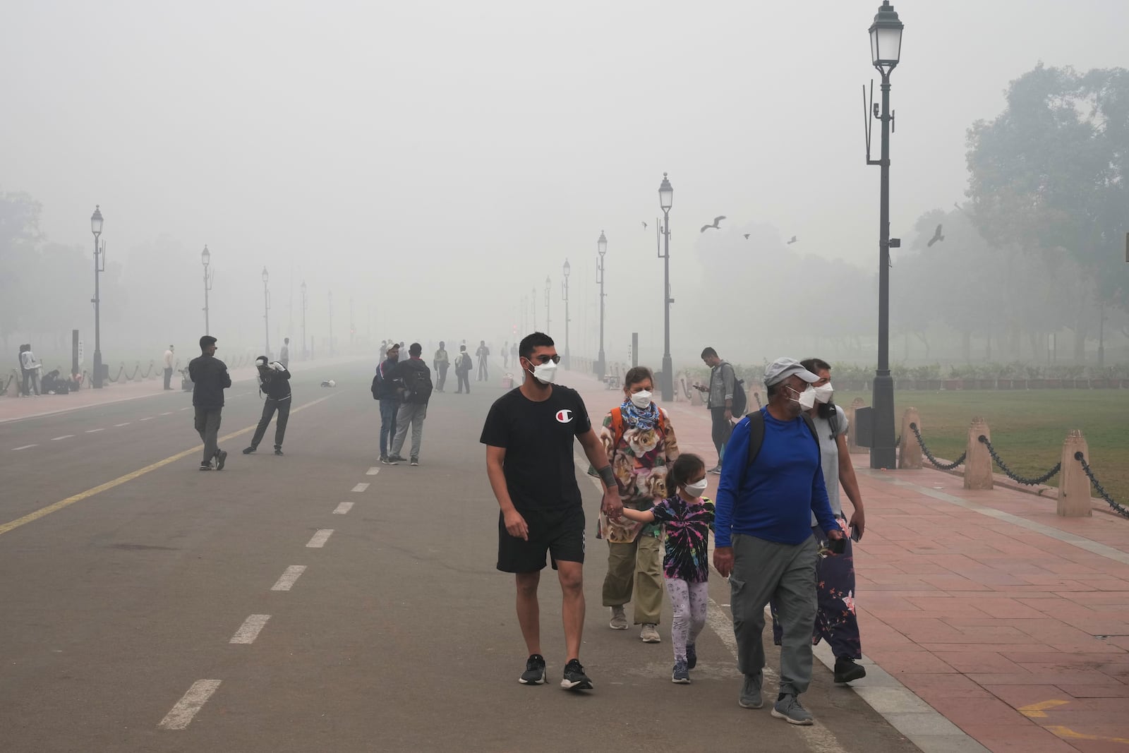 A foreign tourist family walks wearing face mask amidst a thick layer of smog as air pollution shoots up in New Delhi, India, Monday, Nov. 18, 2024. (AP Photo/Manish Swarup)