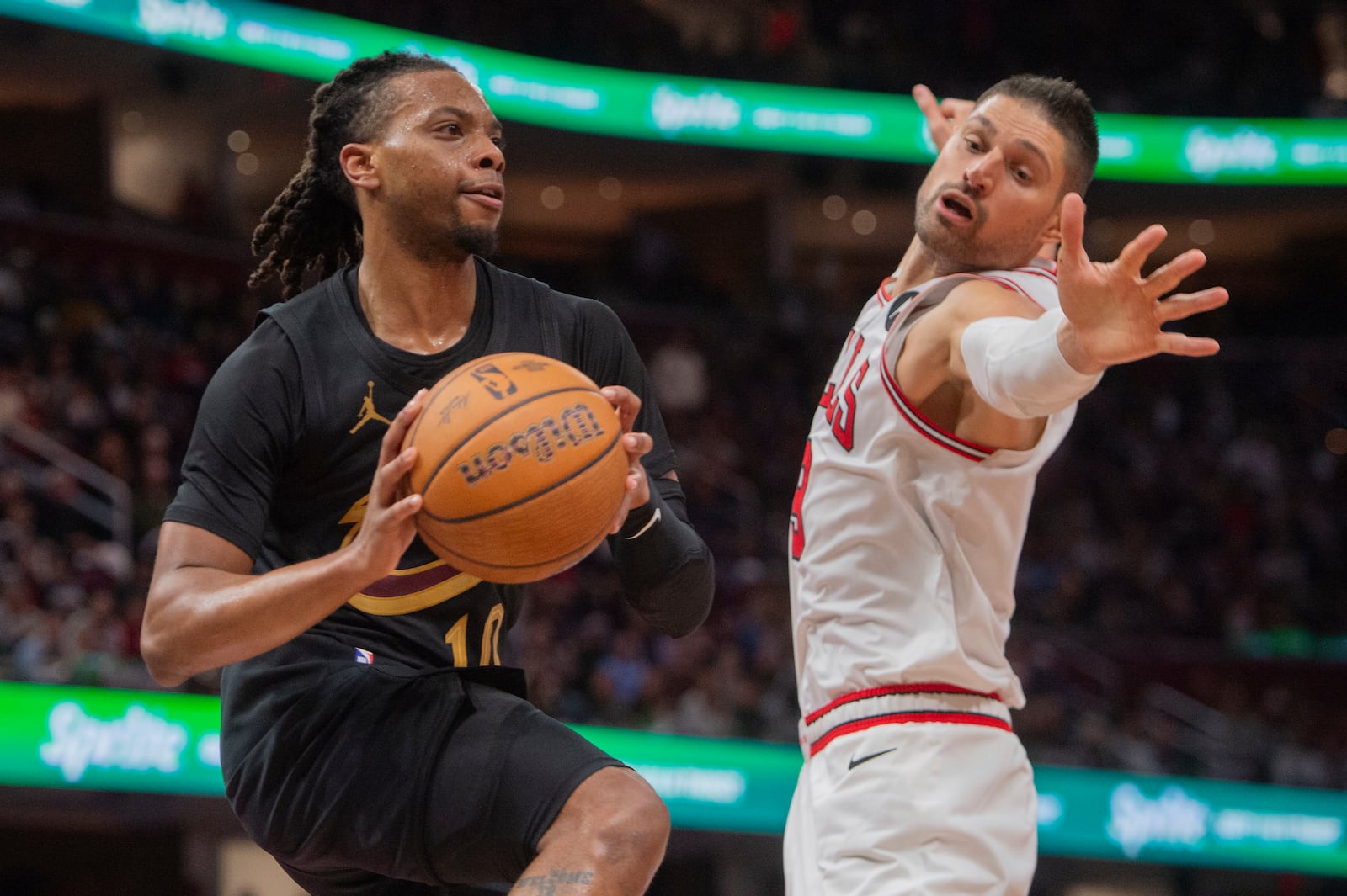 Cleveland Cavaliers' Darius Garland, left, looks to pass the ball past Chicago Bulls' Nikola Vucevic, right, during the second half of an Emirates NBA cup basketball game in Cleveland, Friday, Nov 15, 2024. (AP Photo/Phil Long)