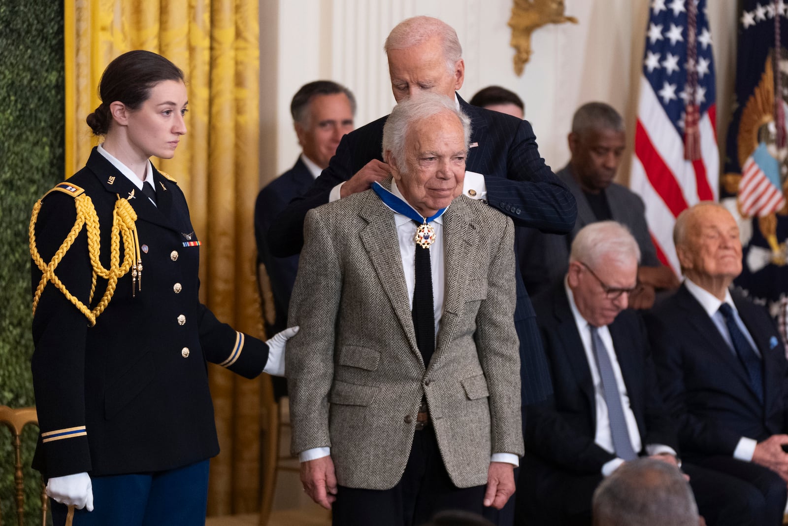 FILE - Army Capt. Rebecca M. Lobach, from left, of Durham, N.C., escorts fashion designer Ralph Lauren as President Joe Biden presents Lauren with the Presidential Medal of Freedom in the East Room of the White House, Jan. 4, 2025, in Washington. (AP Photo/Manuel Balce Ceneta, File)