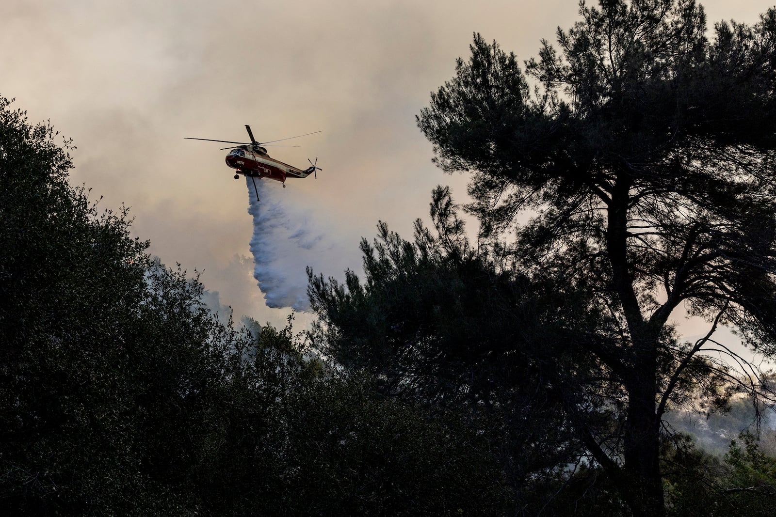 A firefighting helicopter releases water on a hot spot while battling the Palisades Fire in Topanga, Calif., Thursday, Jan. 9, 2025.(Stephen Lam/San Francisco Chronicle via AP)