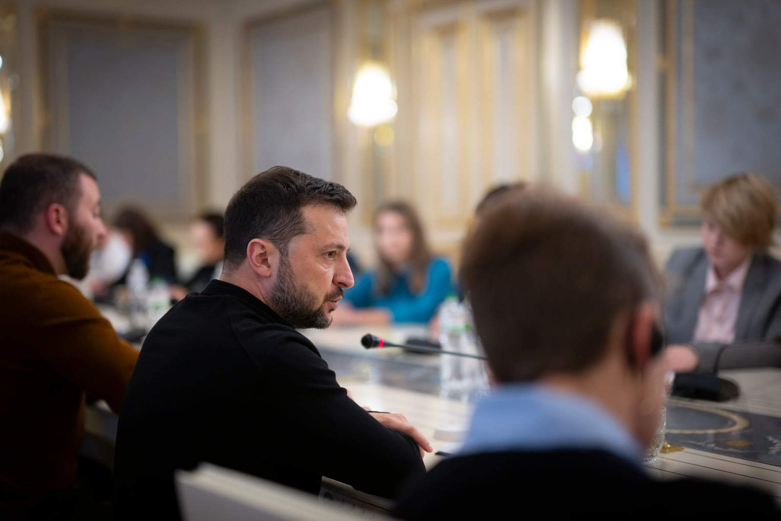 In this photo provided by the Ukrainian Presidential Press Office, Ukrainian President Volodymyr Zelenskyy, left, talks with Ukrainian journalists in Kyiv, Ukraine, Monday, Oct. 21, 2024. (Ukrainian Presidential Press Office via AP)